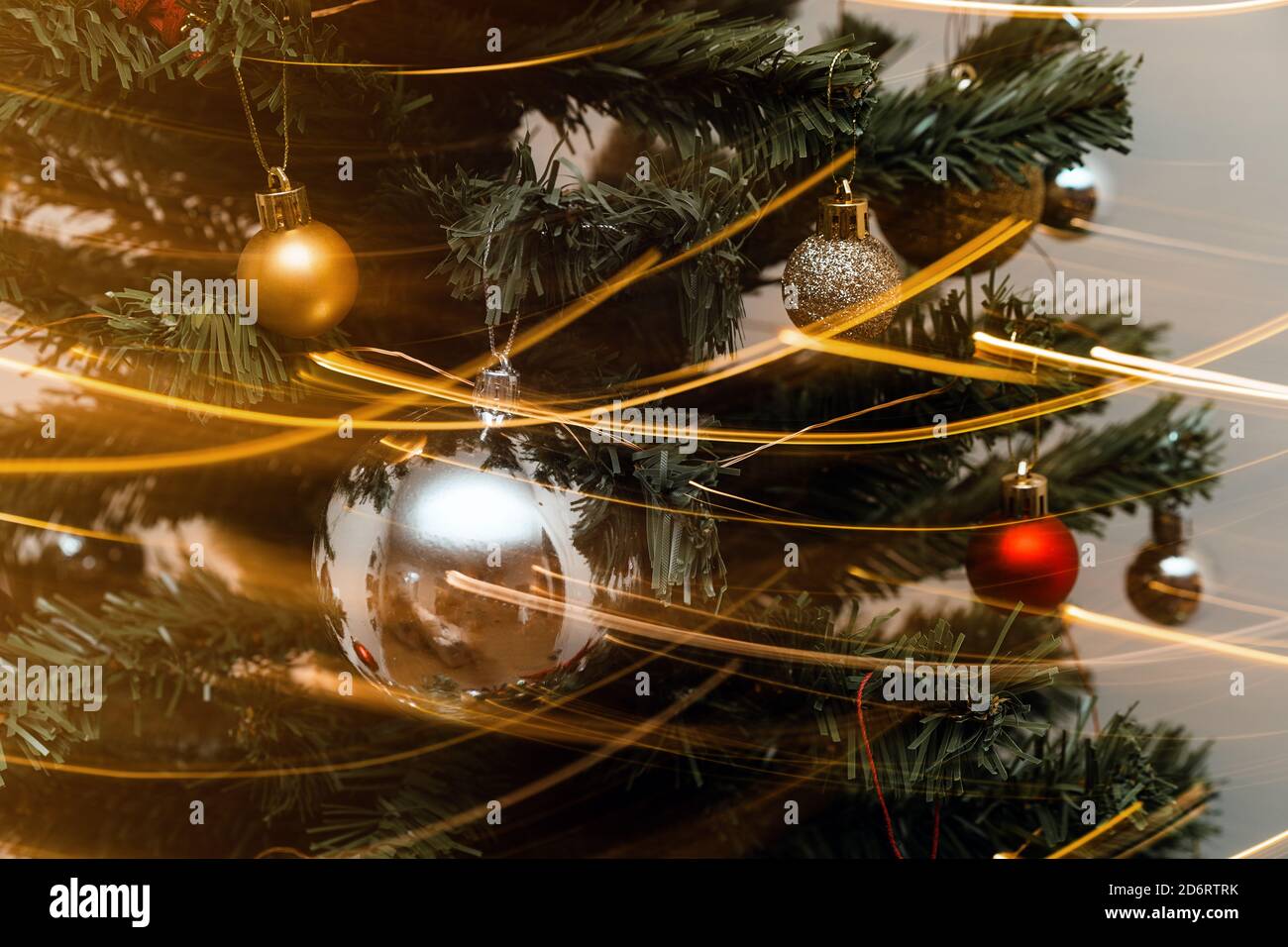 Detail von Weihnachtsbaum mit dekorativen bunten Kugeln und glühenden Girlande in Langzeitbelichtung Stockfoto