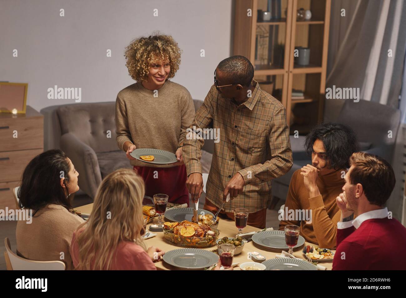 Ortrait von lächelnden afroamerikanischen Mann schneiden gerösteten truthahn während genießen Thanksgiving Abendessen mit Freunden und Familie, Copy Space Stockfoto