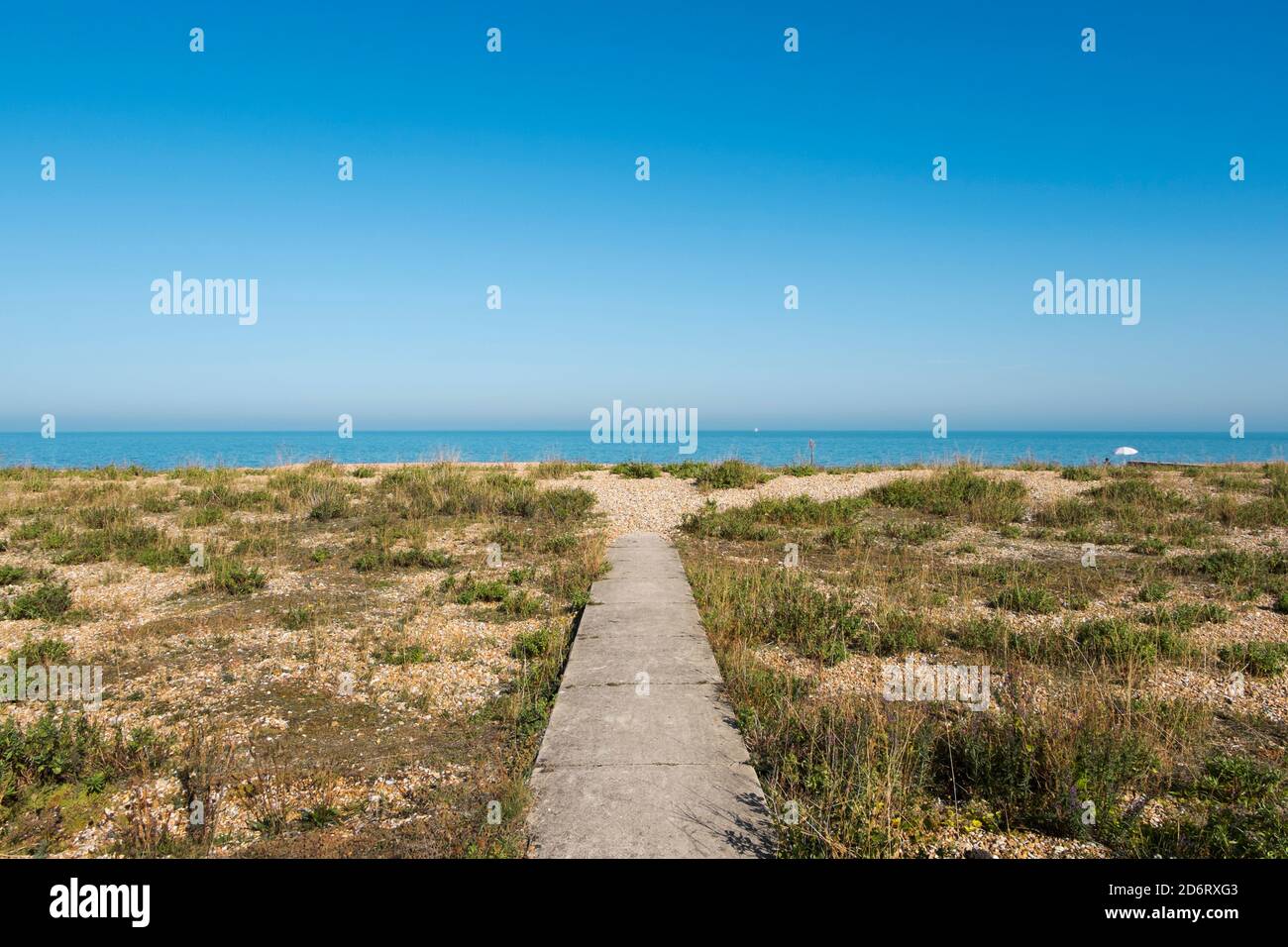 Ein einsamer weißer Regenschirm am Ende eines Gehwegs an einem einsamen Strand in Kingsdown, Deal, Kent, Großbritannien Stockfoto