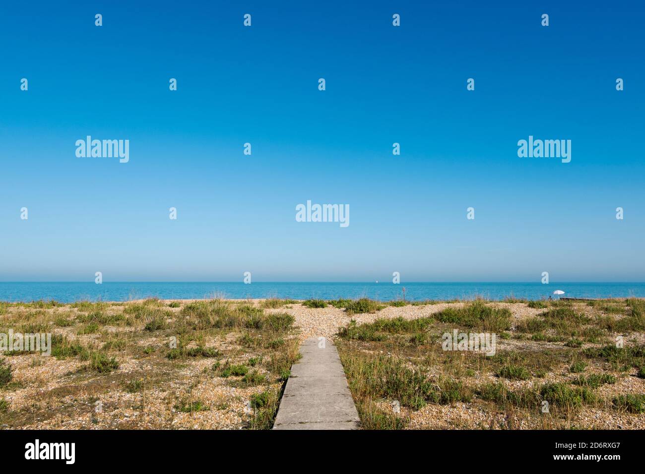 Ein einsamer weißer Regenschirm am Ende eines Gehwegs an einem einsamen Strand in Kingsdown, Deal, Kent, Großbritannien Stockfoto