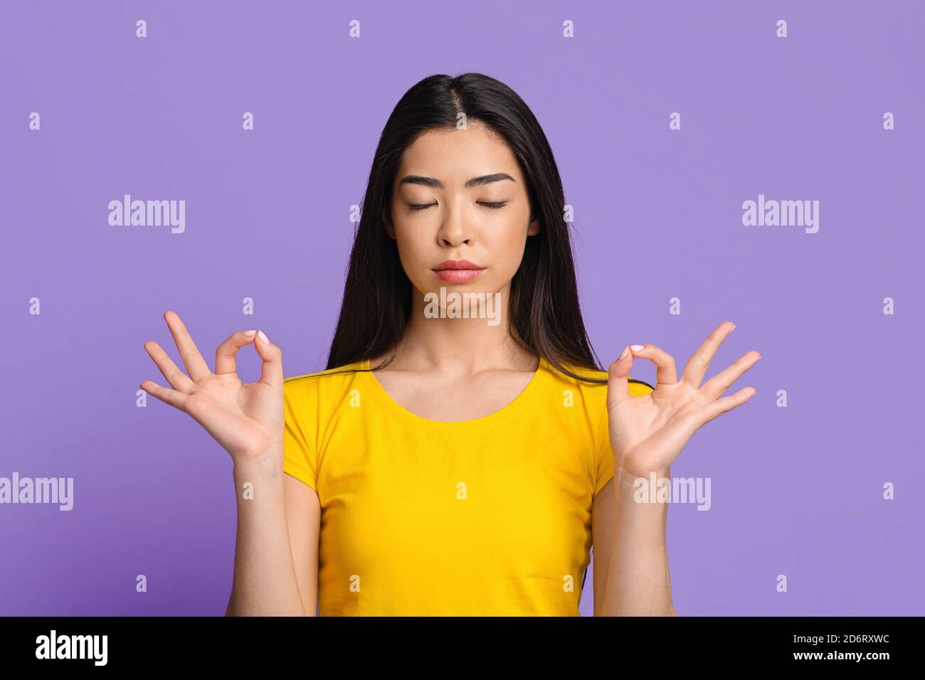 Friedliche afrikanische Frau bleibt ruhig, meditiert auf gelbem Studiohintergrund Stockfoto