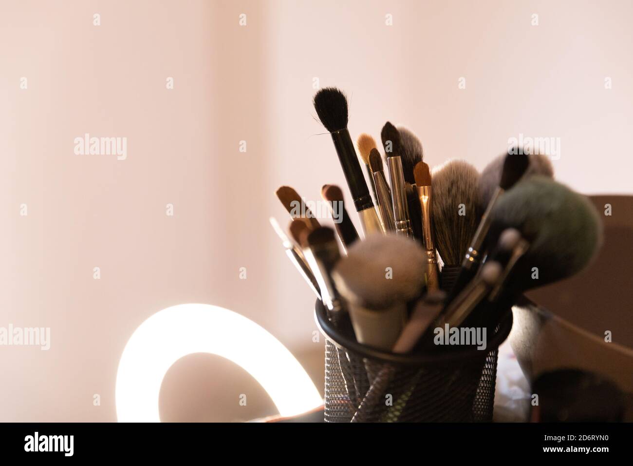 Sammlung von verschiedenen Make-up-Bürsten in Halter auf dem Tisch platziert In der Nähe Lampe in modernen Beauty-Studio Stockfoto