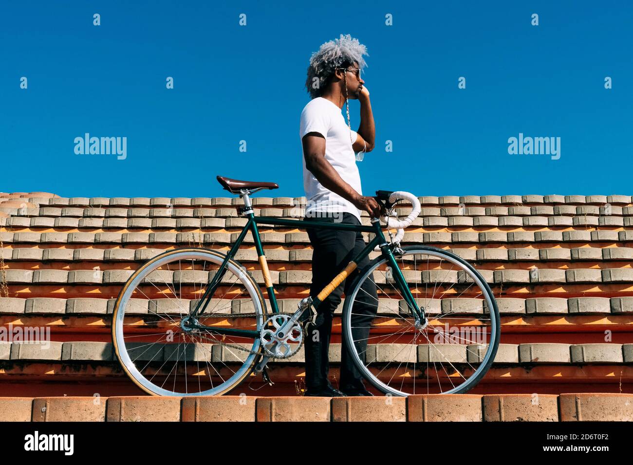 Afro und schwarzer Mann, der das Fahrrad auf einigen Treppen trägt. Black Rider Konzept. Radfahren in der Stadt. Stockfoto