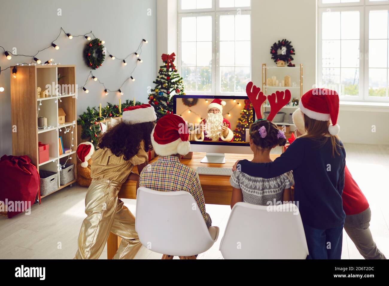 Gruppe von Kindern hören Videoaufzeichnung des Weihnachtsmanns online mit Web-Chat-Telefonkonferenz im Weihnachtszimmer. Stockfoto