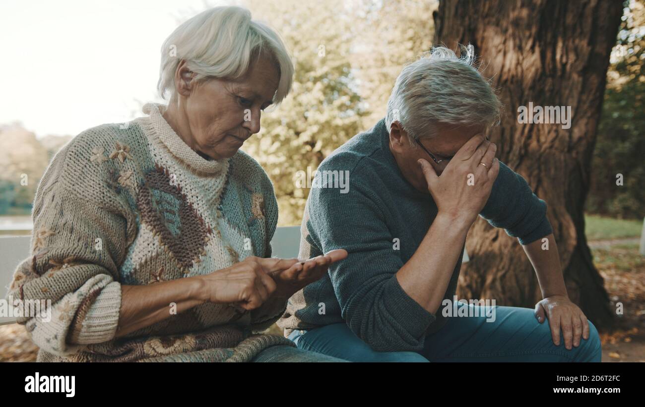 Ältere besorgt Paar sitzt auf der Bank in Verzweiflung. Frau zählt die letzten Münzen. Hochwertige Fotos Stockfoto
