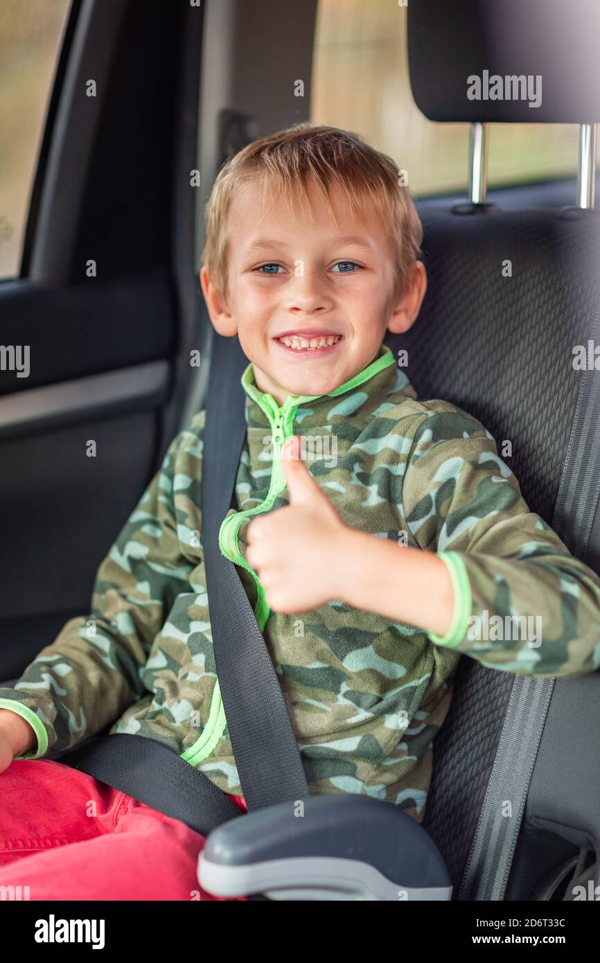 Kleiner Junge, der auf einem Sitzerhöhung sitzt, schnallte sich im Auto an.  Sicherheit des Kindersitzes Stockfotografie - Alamy