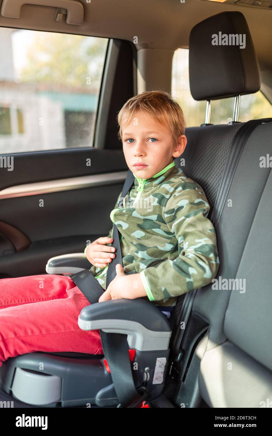 Kleiner Junge, der auf einem Sitzerhöhung sitzt, schnallte sich im Auto an.  Sicherheit des Kindersitzes Stockfotografie - Alamy