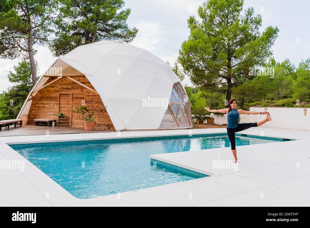 Seitenansicht der flexiblen barfuß-Hündin in Sportswear im Stehen Ausgestreckte Hand bis zur großen Zehe Pose in der Nähe des Schwimmbades Stockfoto