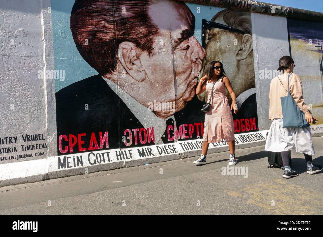 Touristen bei Graffiti auf dem Originalteil der Berliner Mauer In der East Side Gallery in Friedrichshain Berlin Street Art Stockfoto