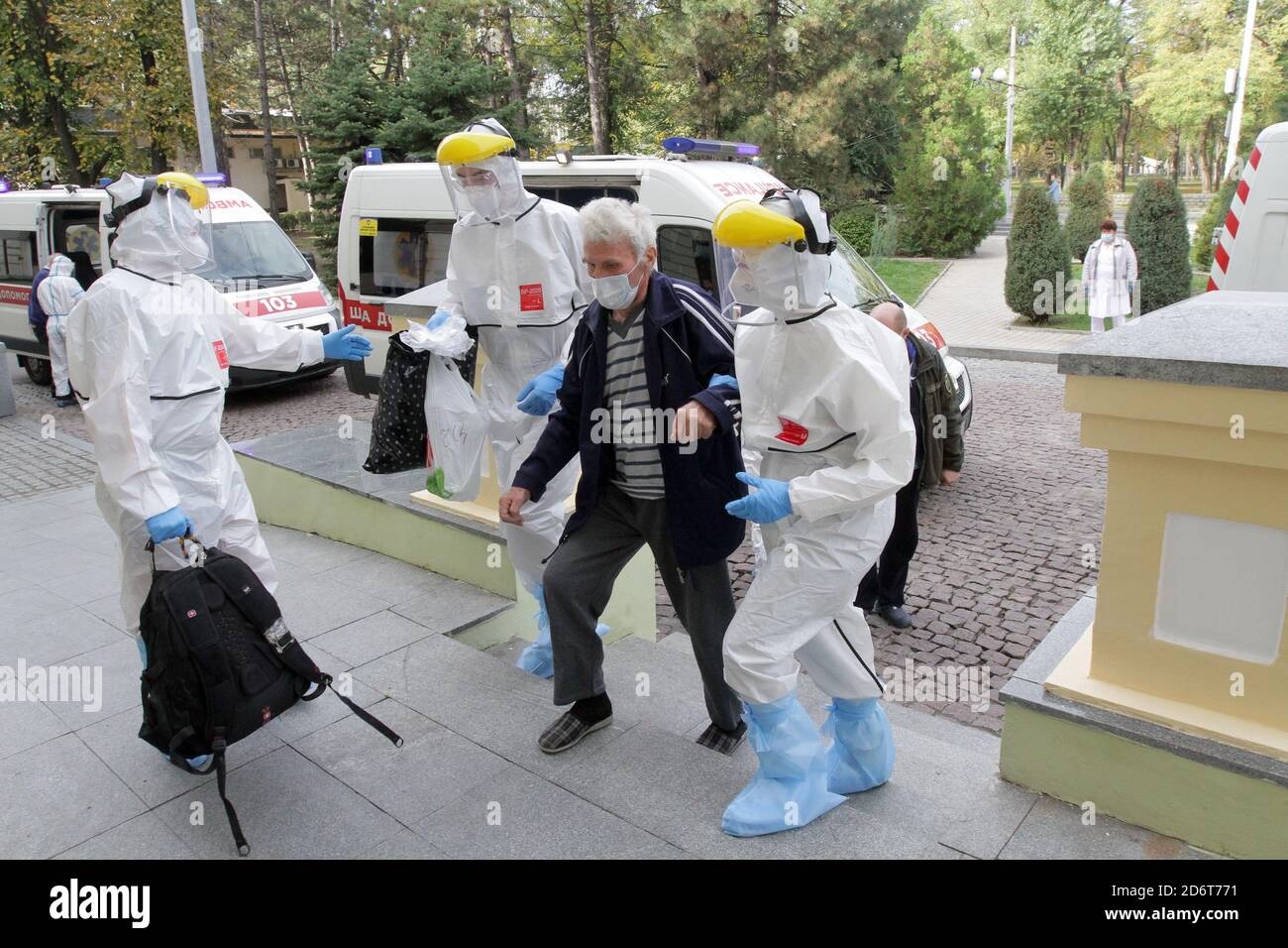 Non Exclusive: DNIPRO, UKRAINE - 19. OKTOBER 2020 - Gesundheitsarbeiter in Schutzanzügen helfen einem älteren Mann zu Fuß als die therapeutische Abteilung der Stockfoto