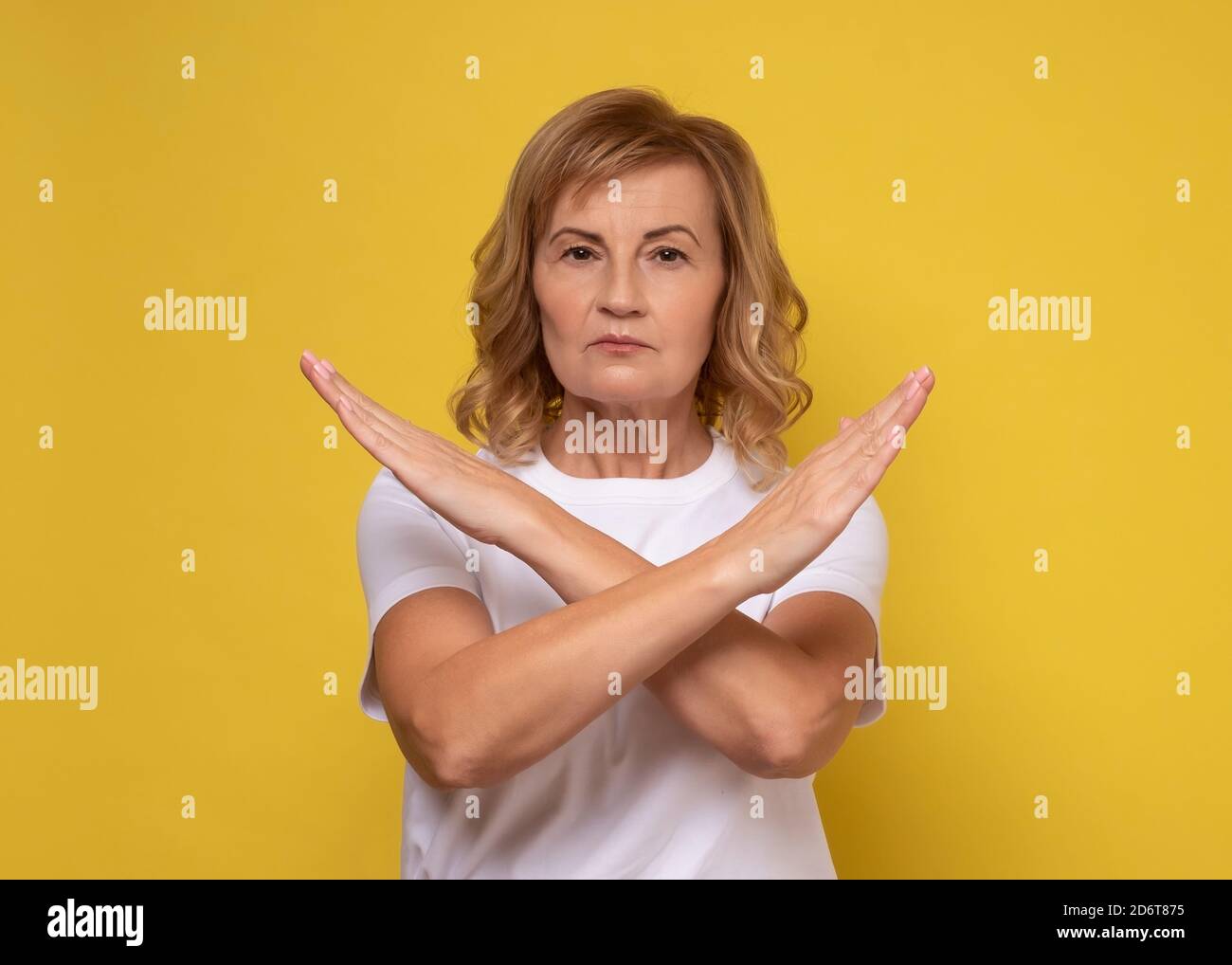 Reife Frau macht X-Zeichen mit gekreuzten Händen, gestikulierenden Stopp, Warnung vor Gefahr. Stockfoto