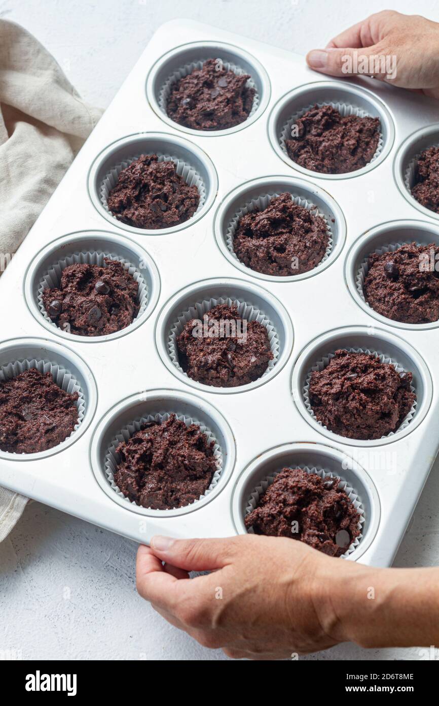 Von oben Schokolade Muffin Teig in Muffin Fall beim Backen Pfanne in der hellen Küche Stockfoto