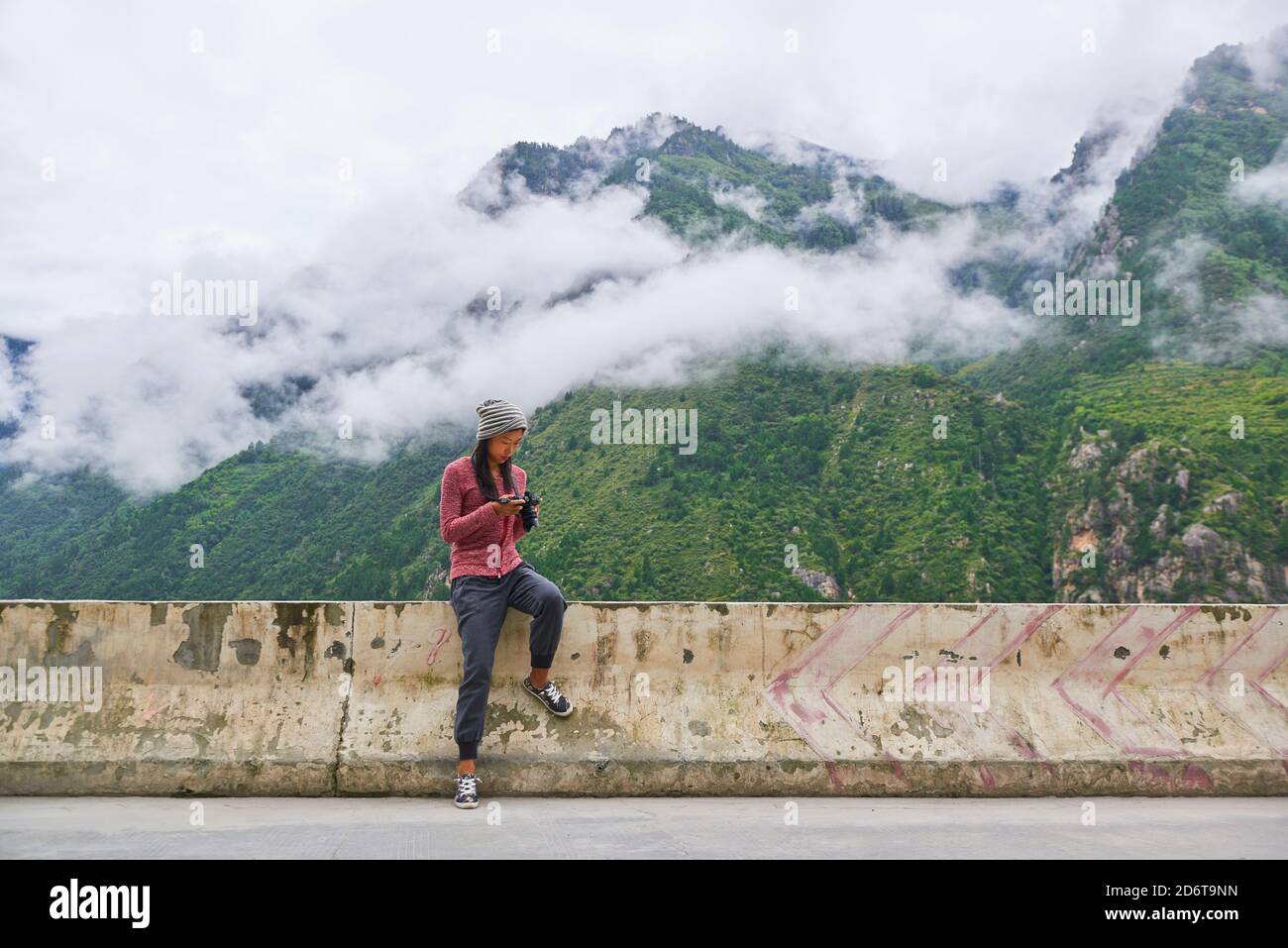 Junge asiatische Frau in sportlichem Outfit auf Steinterrasse ruhen In malerischen, neblig grünen Bergen Stockfoto