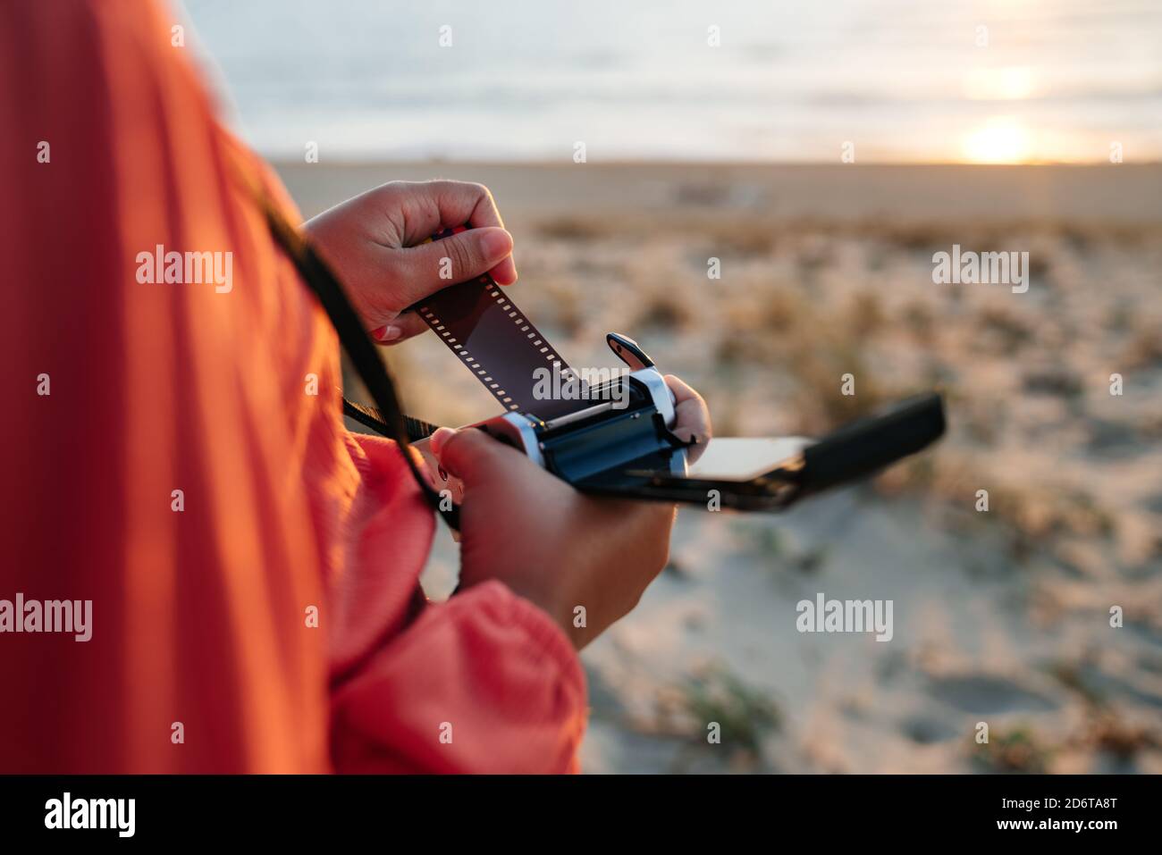 Von oben der Ernte anonyme weibliche Reisende Einstellung vintage Film Kamera beim Sonnenuntergang am Sandstrand Stockfoto