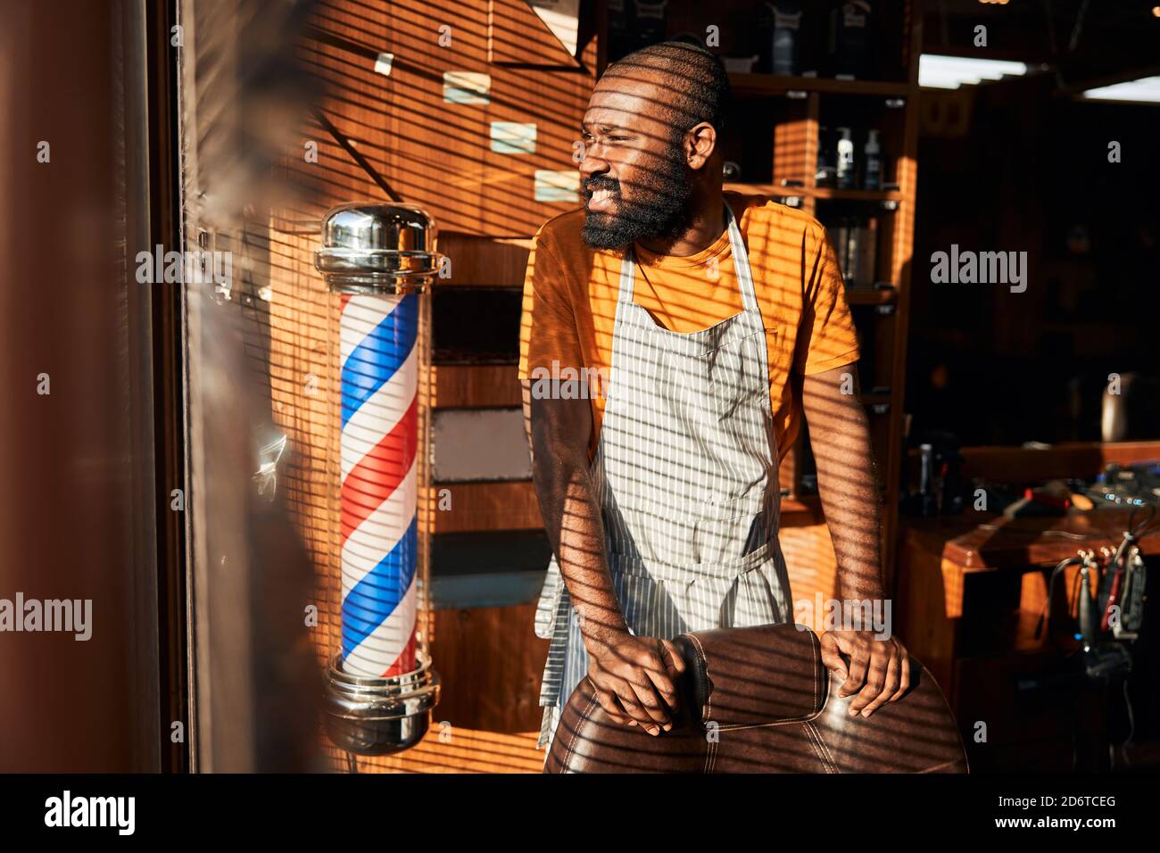 Bärtiger afroamerikanischer Mann, der im Friseurladen am Fenster steht Stockfoto