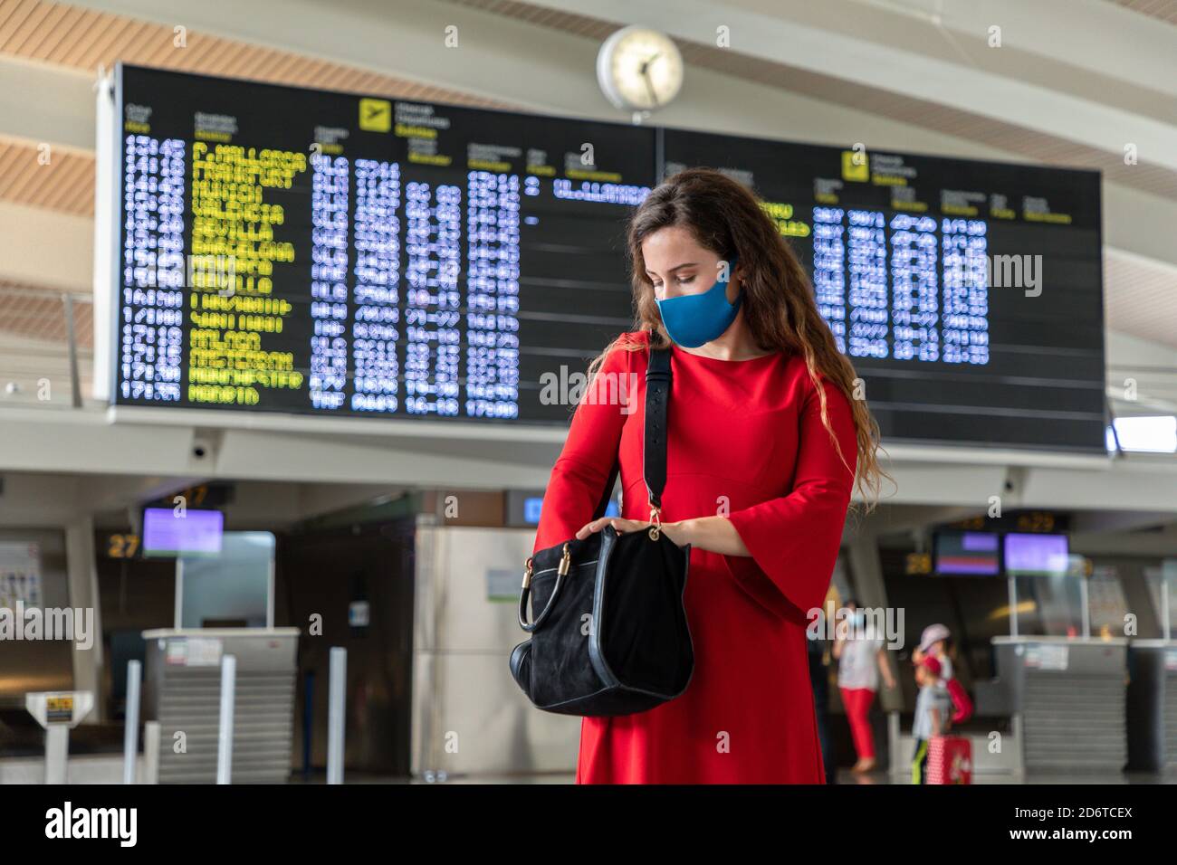 Weibliche Touristen tragen Schutzmaske stehen im Flughafen gegen Abreise Gehen Sie an Bord und überprüfen Sie Ihre Tasche, während Sie während des Coronavirus auf den Flug warten Epidem Stockfoto