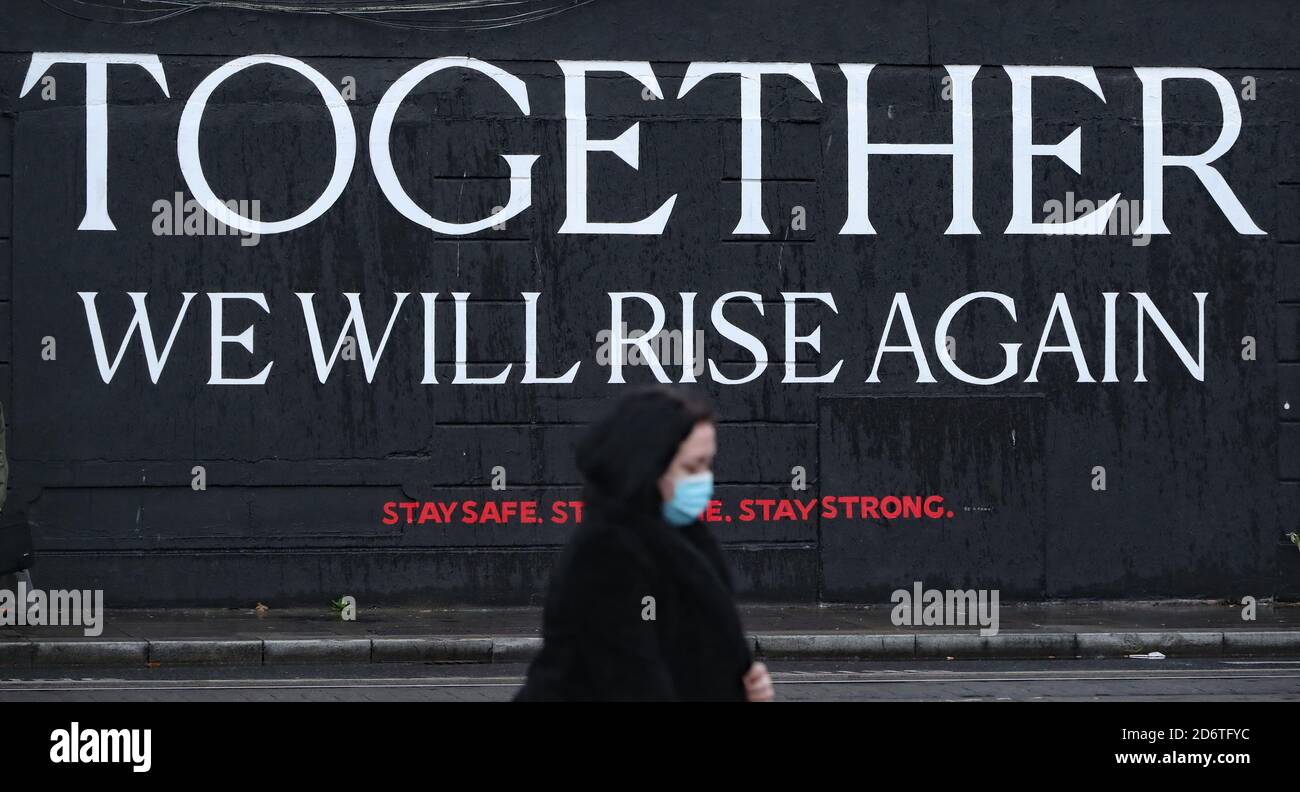 Eine Frau passiert ein Wandgemälde im Stadtzentrum von Dublin, da die irische Regierung voraussichtlich Pläne zur Einführung weiterer landesweiter Beschränkungen hinsichtlich der steigenden Zahl von Coronavirus-Fällen abzeichnen wird. Stockfoto