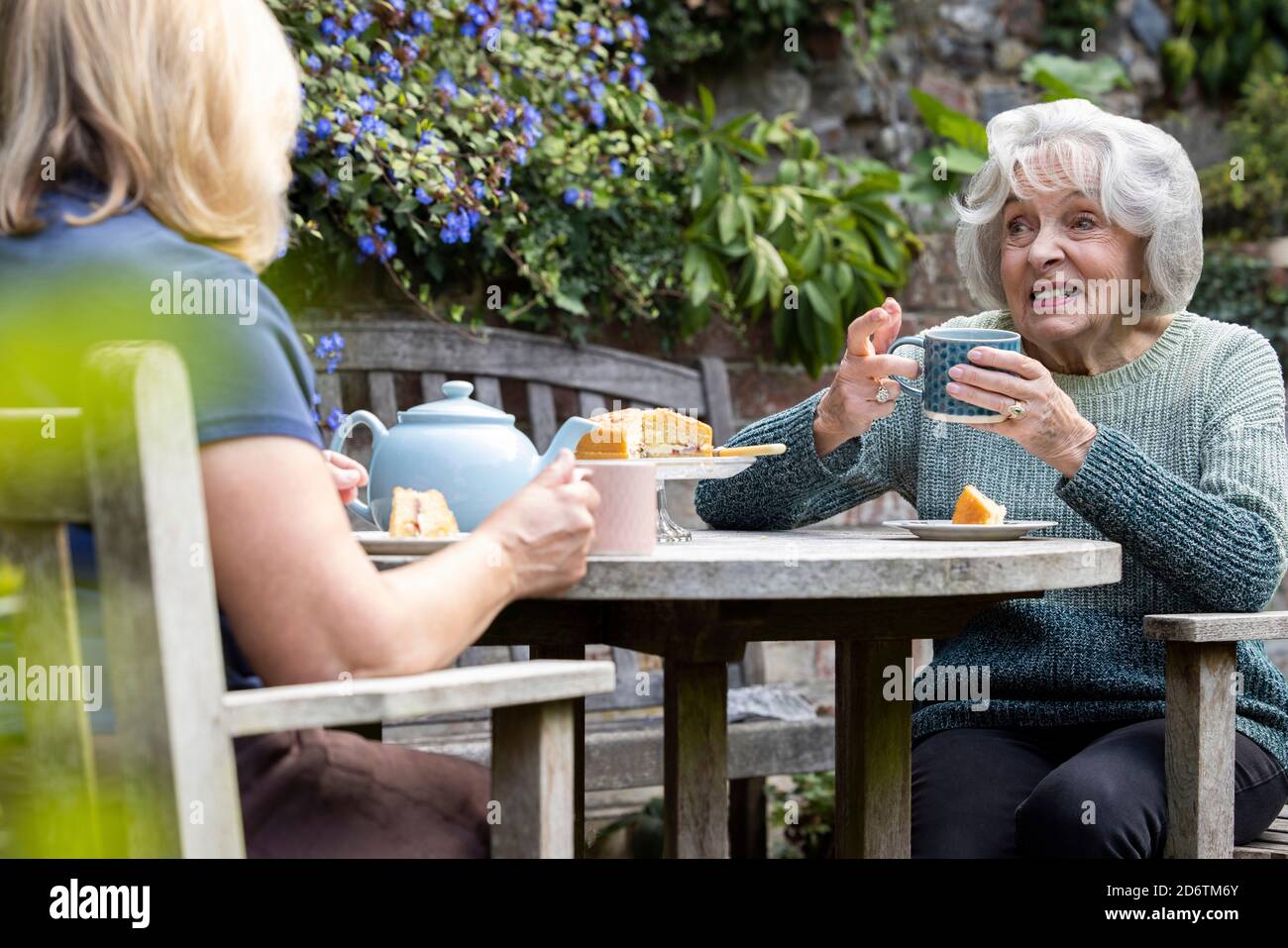 Ältere Frau Besucht Einsame Ältere Mutter Im Garten Während Der Sperre Stockfoto