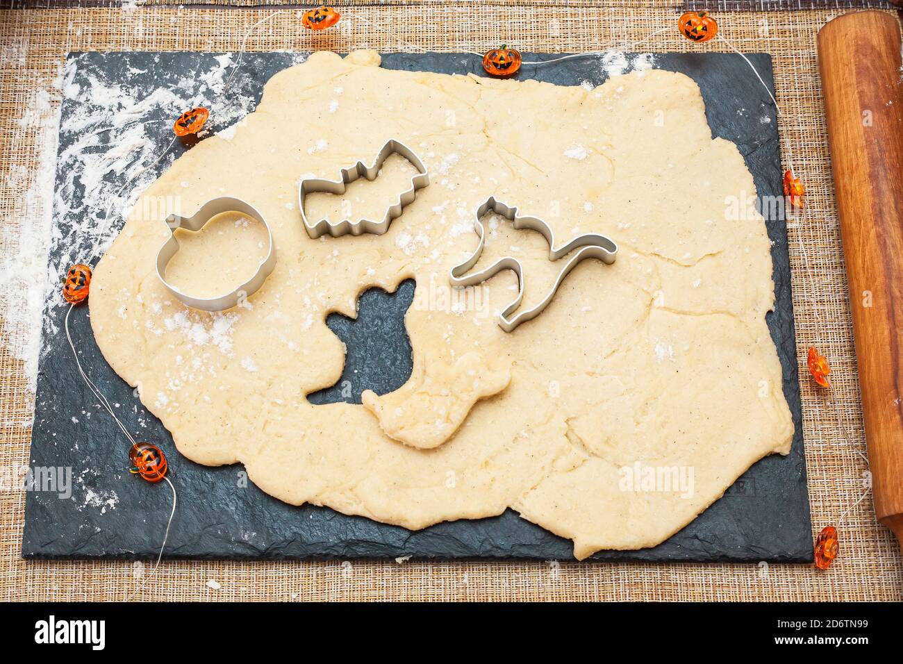 Cookies für Halloween machen. Kekse aus dem Teig in Form von Kürbis, Katze, Geist und Fledermaus ausschneiden. Stockfoto