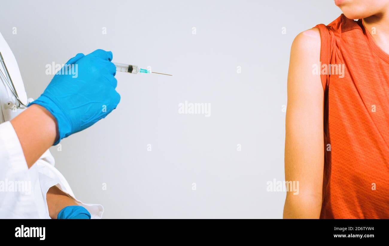 Arzt impfen Kind für Coronavirus in der Klinik. Spritze mit Handschuhen geschützte Hände. Stockfoto