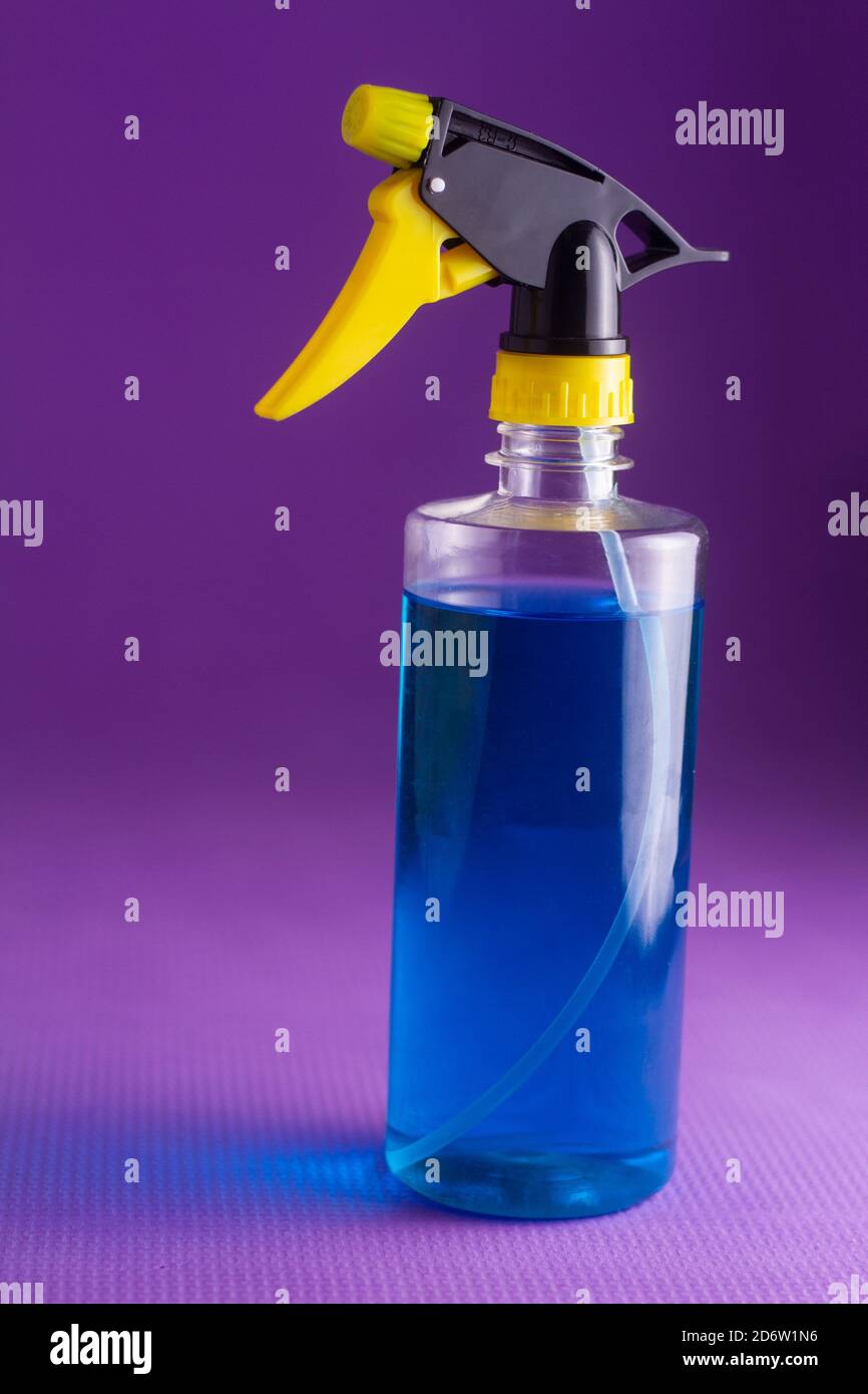 Blaue Hand Desinfektionsmittel Sprühflasche auf violettem Hintergrund Stockfoto