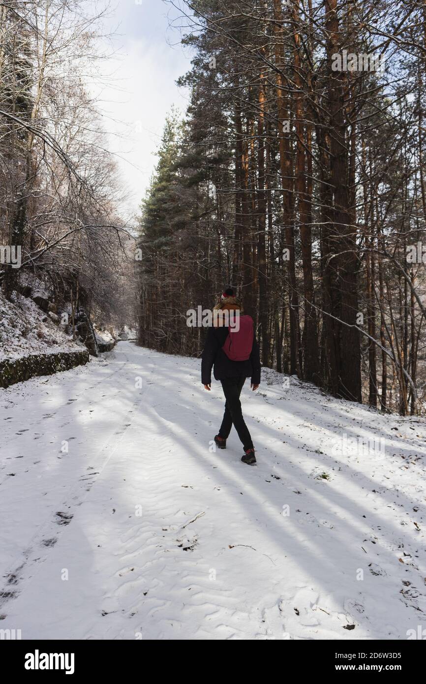 Junger Mann, der auf einer verschneiten Straße in den Berg geht. Rila Berg, Bulgarien. Geschlossene Straße bei schlechtem Winterwetter Stockfoto