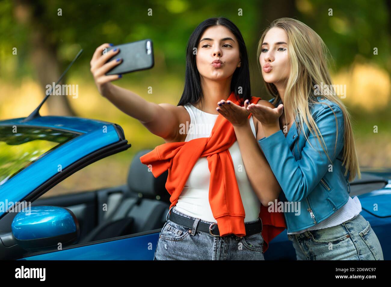 Junge hübsche zwei Frauen Schlag Kuss nehmen ein Selfie während Stehen in der Nähe von Cabrio Auto auf der Straße Stockfoto