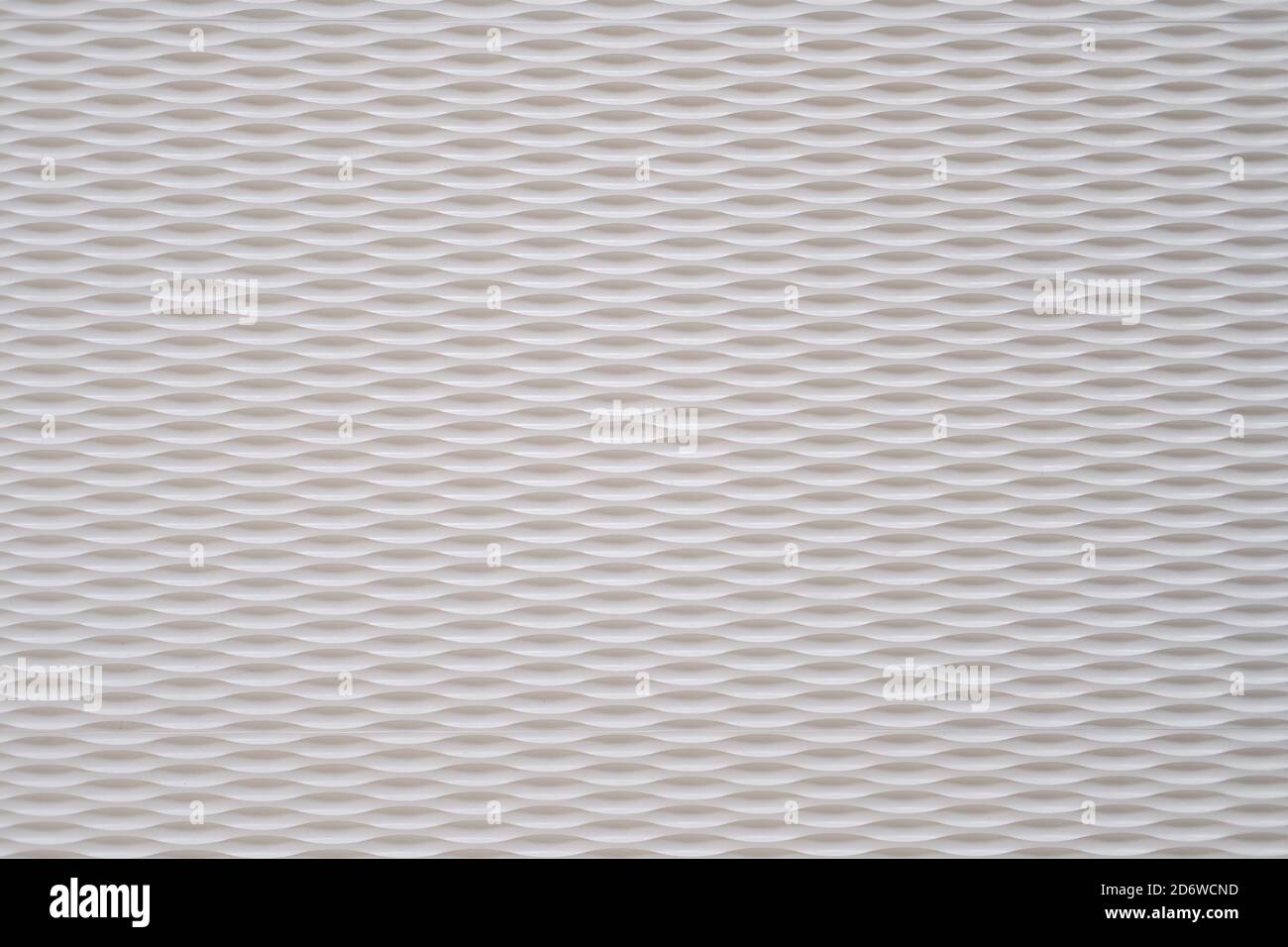 Weißer Wandhintergrund mit ovalen Kerben in geraden Reihen. Futuristische Textur Stockfoto