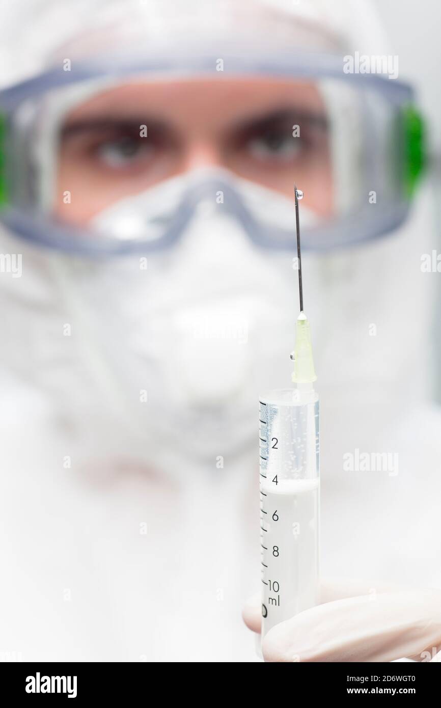 Nahaufnahme des Arztes mit Schutzkleidung Vorbereitung einer Spritze für Impfung - Fokus auf die Nadel Stockfoto
