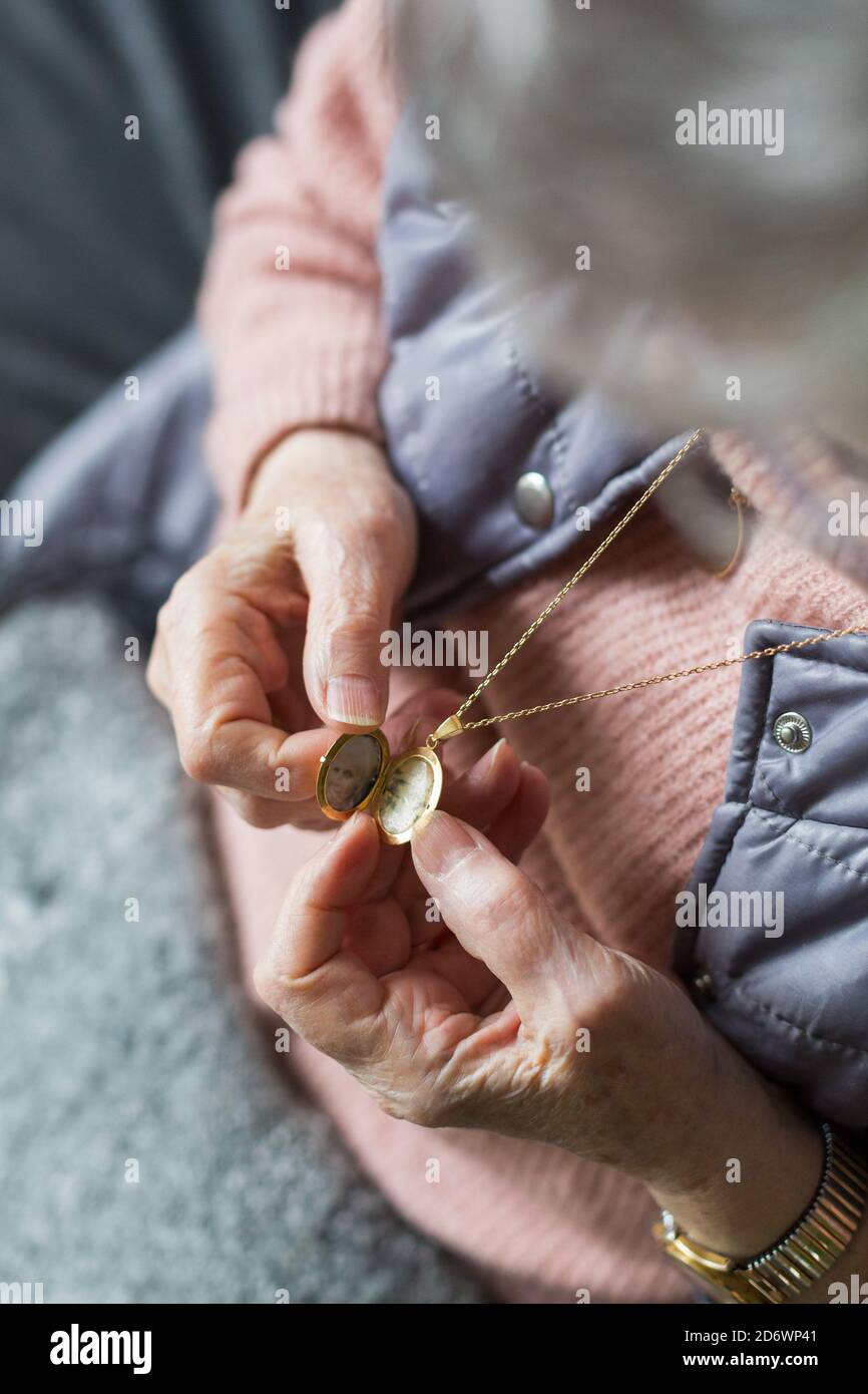 Ältere Frau, die Fotos in einem Medaillon mit Anhänger anschaut. Stockfoto