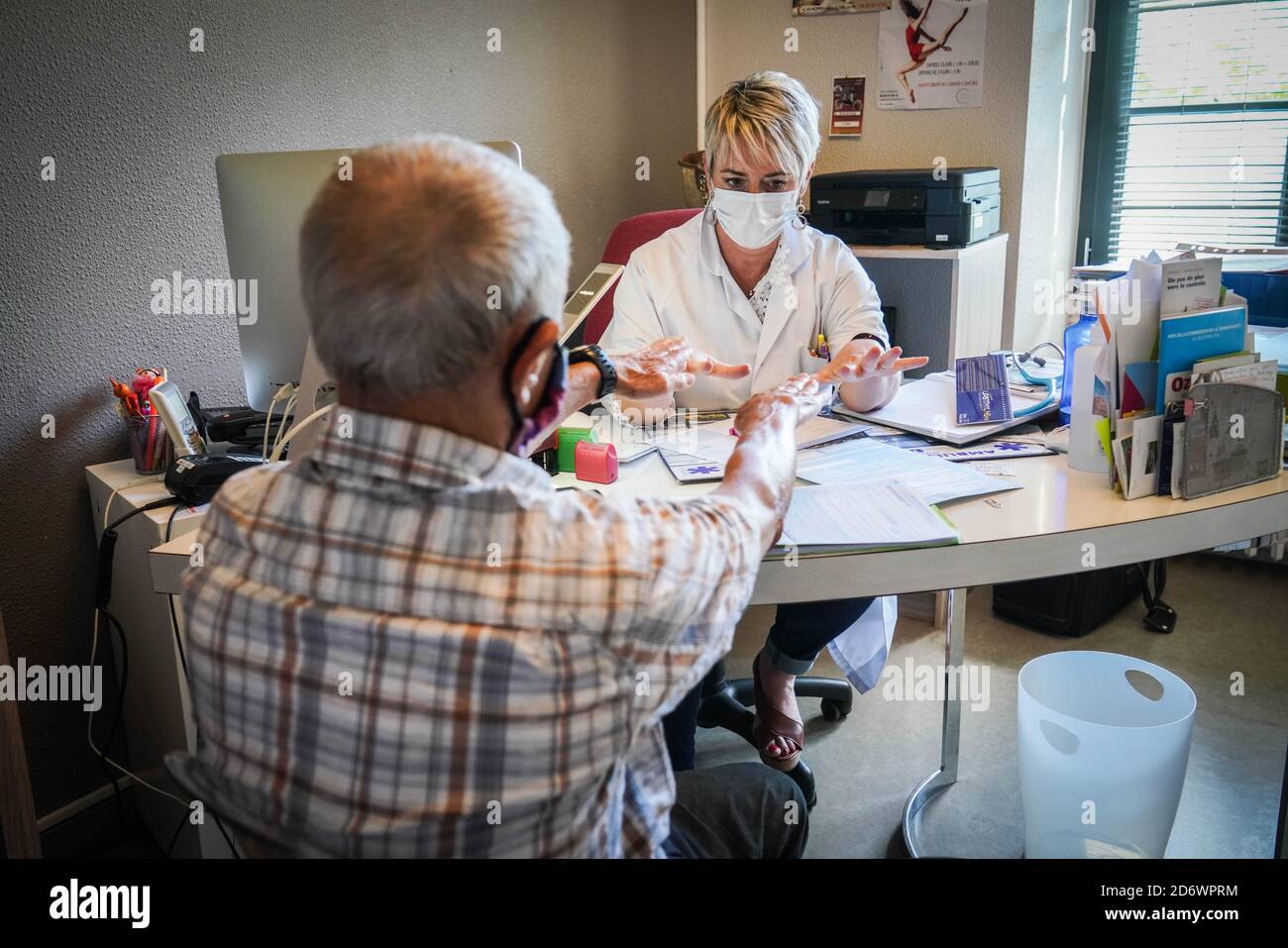 Mann in Absprache mit einem Hausarzt mit einer OP-Maske, Frankreich, Mai 2020. Stockfoto
