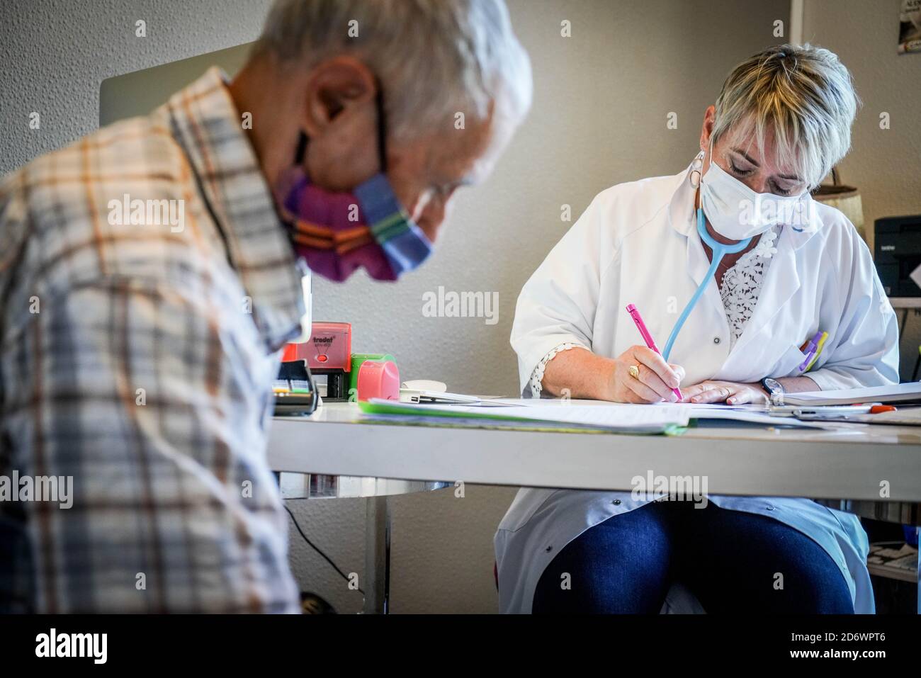 Mann in Absprache mit einem Hausarzt mit einer OP-Maske, Frankreich, Mai 2020. Stockfoto