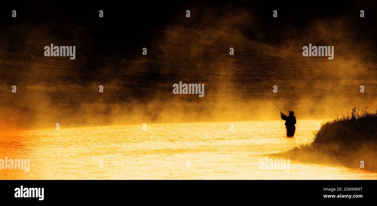 Mann Angeln im Fluss oder See Silhouette bei Sonnenaufgang und Nebliges Wasser Stockfoto