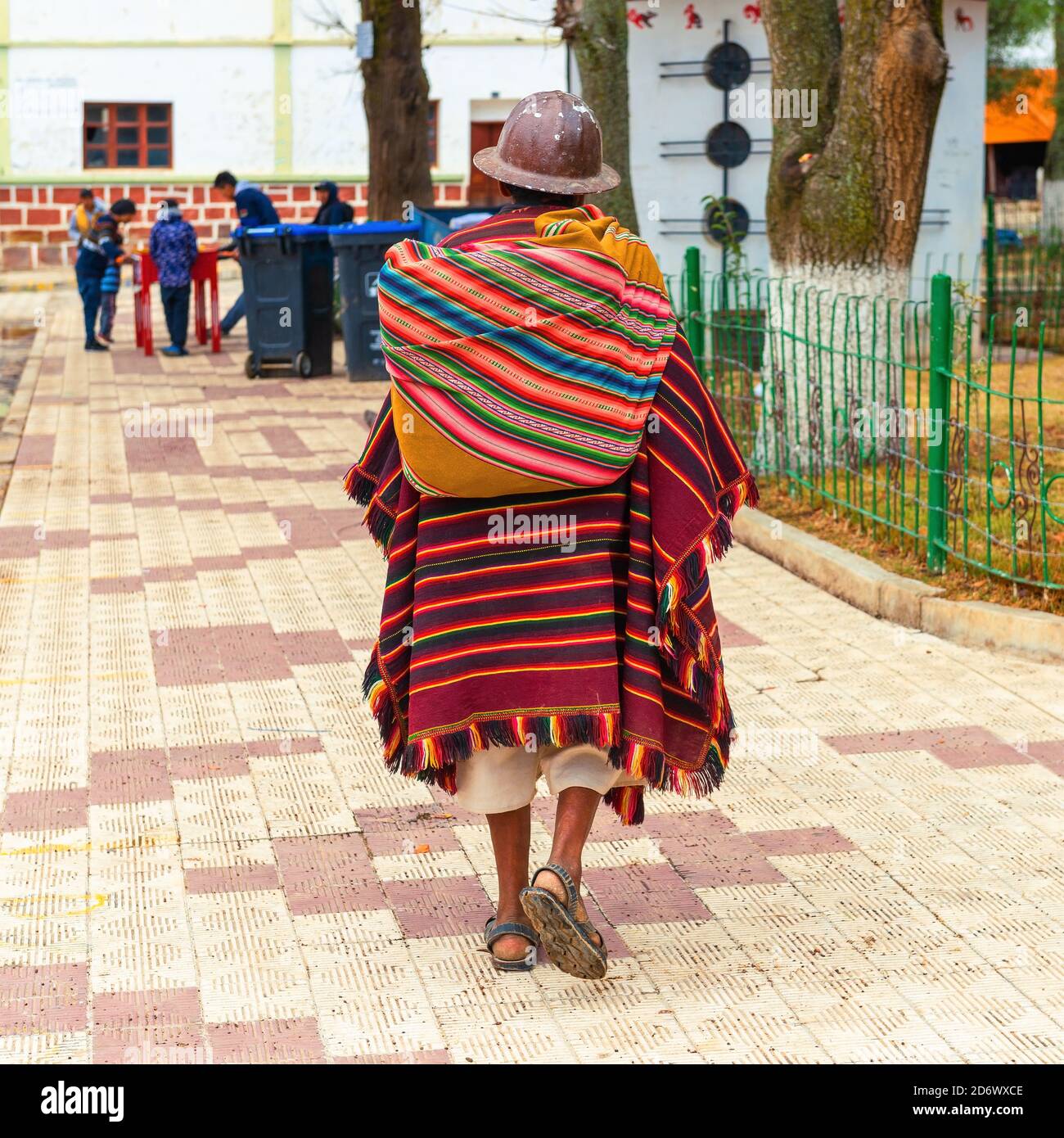 Ältere bolivianische indigene Tarabuco Mann in traditioneller Kleidung (Poncho und Hut) zu Fuß auf dem Hauptplatz, Tarabuco, Bolivien. Stockfoto