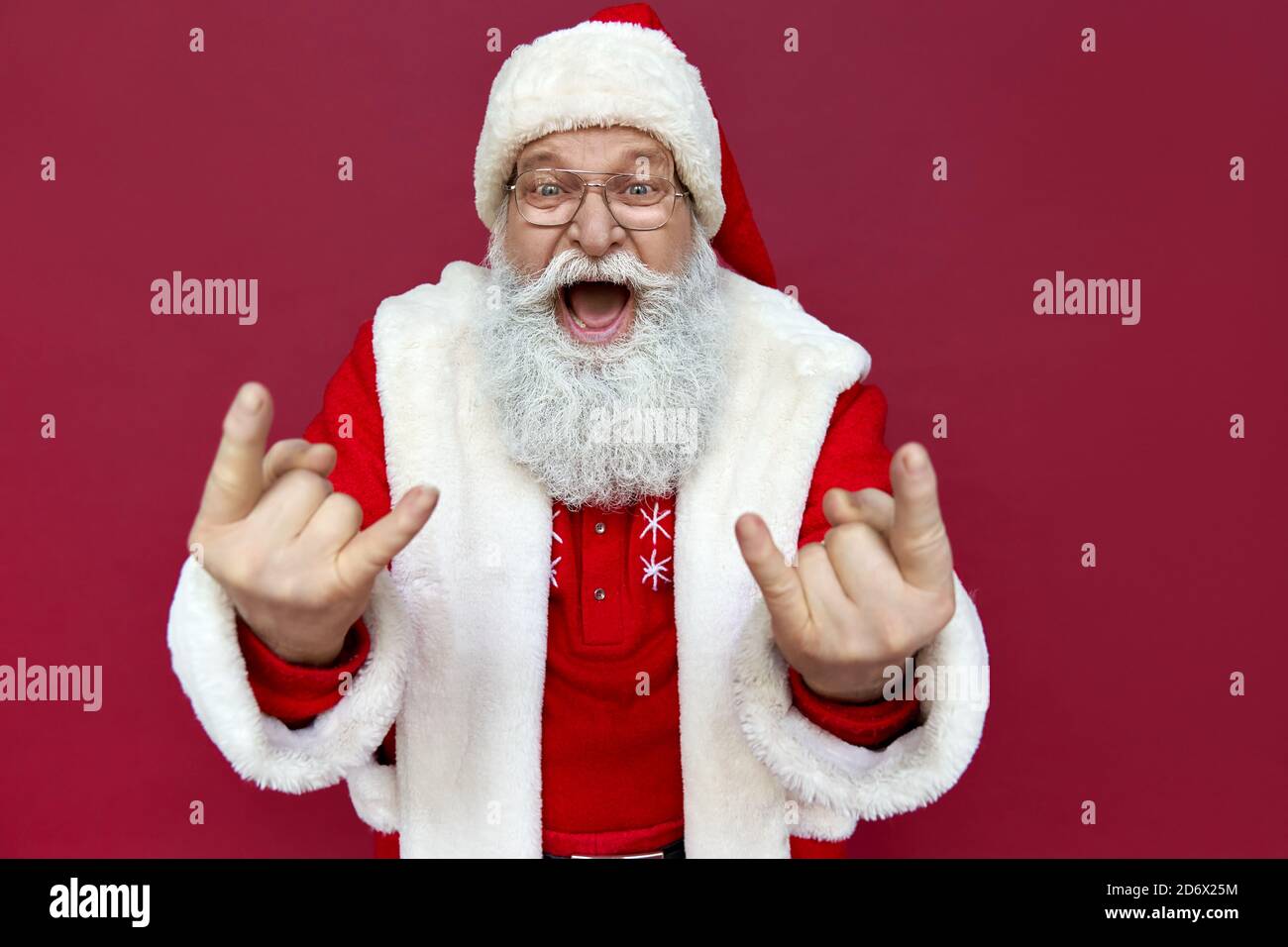 Lustige Weihnachtsmann trägt Kostüm mit Hörnern isoliert auf rotem Hintergrund. Stockfoto