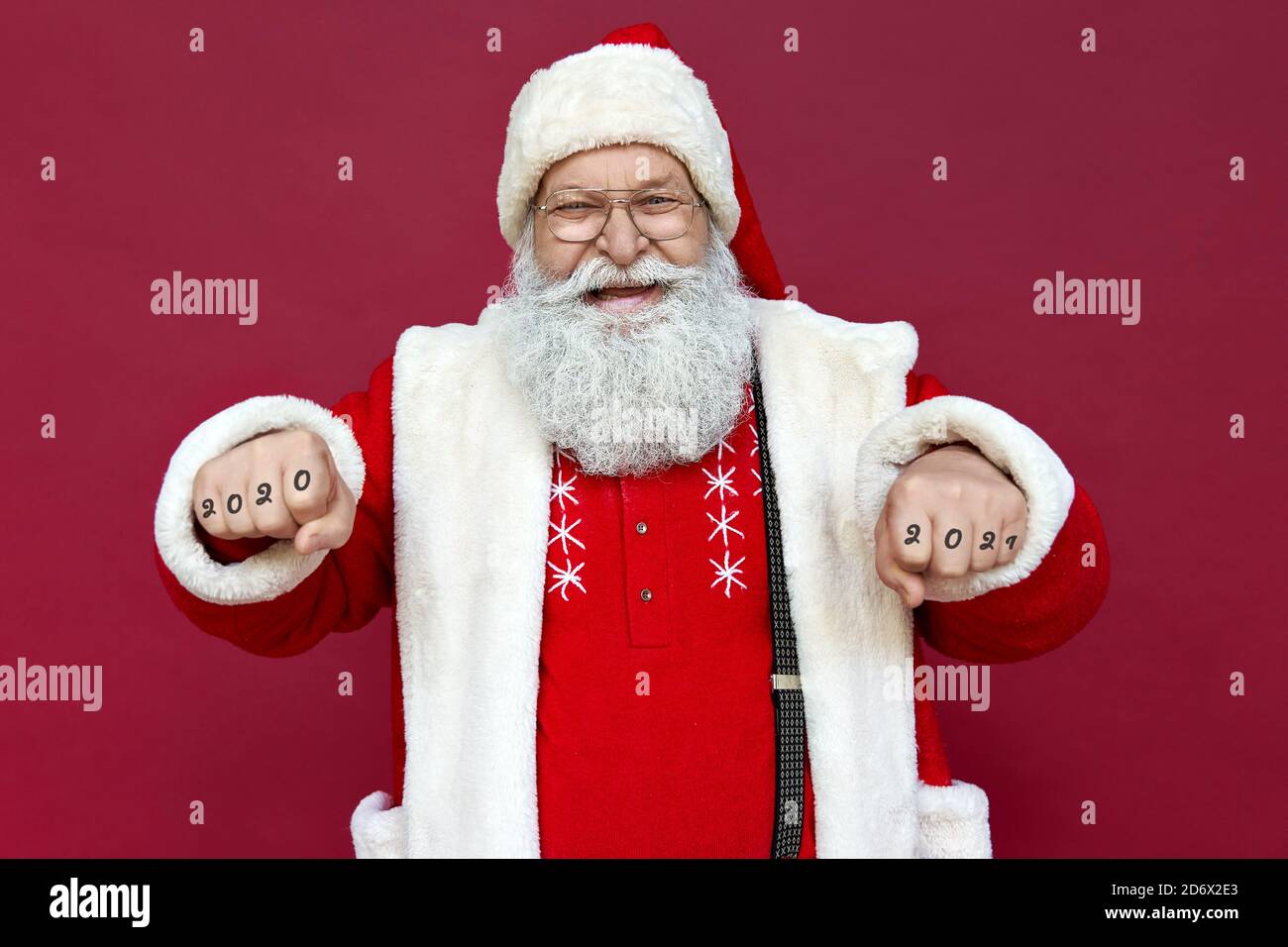 Happy Santa Claus trägt Kostüm mit Fäusten isoliert auf rotem Hintergrund. Stockfoto