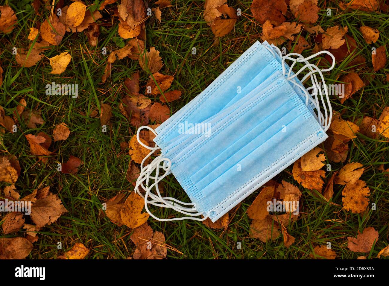 Medizinische Maske blau vor dem Hintergrund der gelb-orange Blätter im Herbst, das Konzept des Beginns einer Welle von Krankheiten Stockfoto