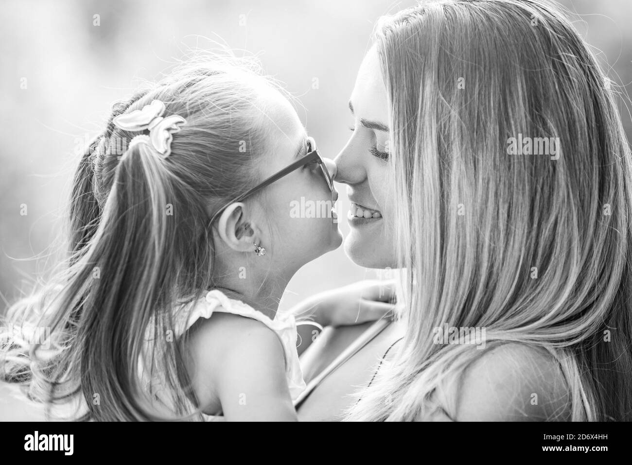 Familiengeneration und Menschenkonzept. Nahaufnahme Porträt der lächelnden Mutter umarmt niedlichen kleinen Tochter. Kleine Tochter umarmt ihre glückliche Mutter. Stockfoto