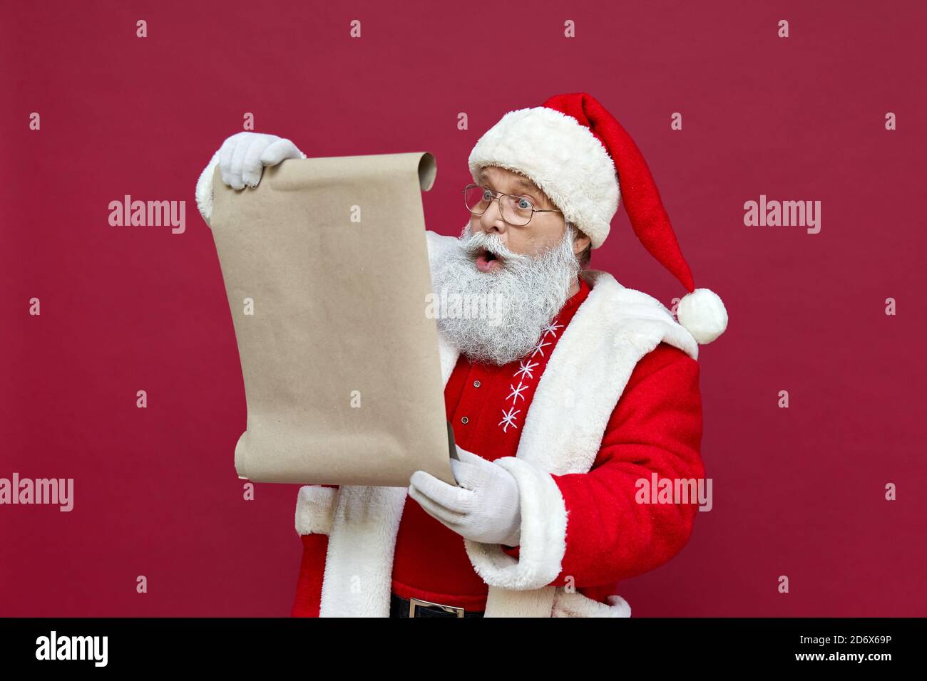 Schockiert Weihnachtsmann trägt Kostüm Lesung Wunschliste auf rotem Hintergrund. Stockfoto