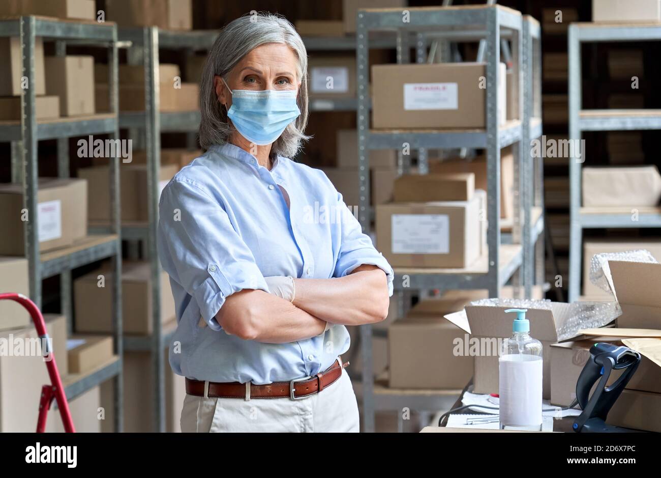 Reife Frau Unternehmer trägt Gesichtsmaske im Lager stehen, Porträt. Stockfoto