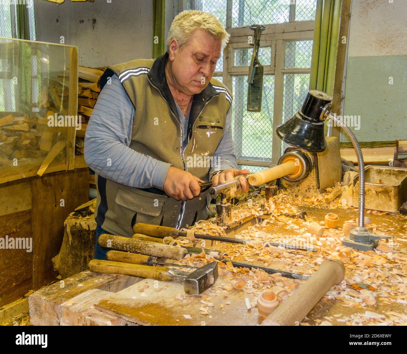 Holzwender schnitzt matrjoschka (russische hölzerne Nistpuppe) in der Werkstatt. Puppenherstellung Stockfoto