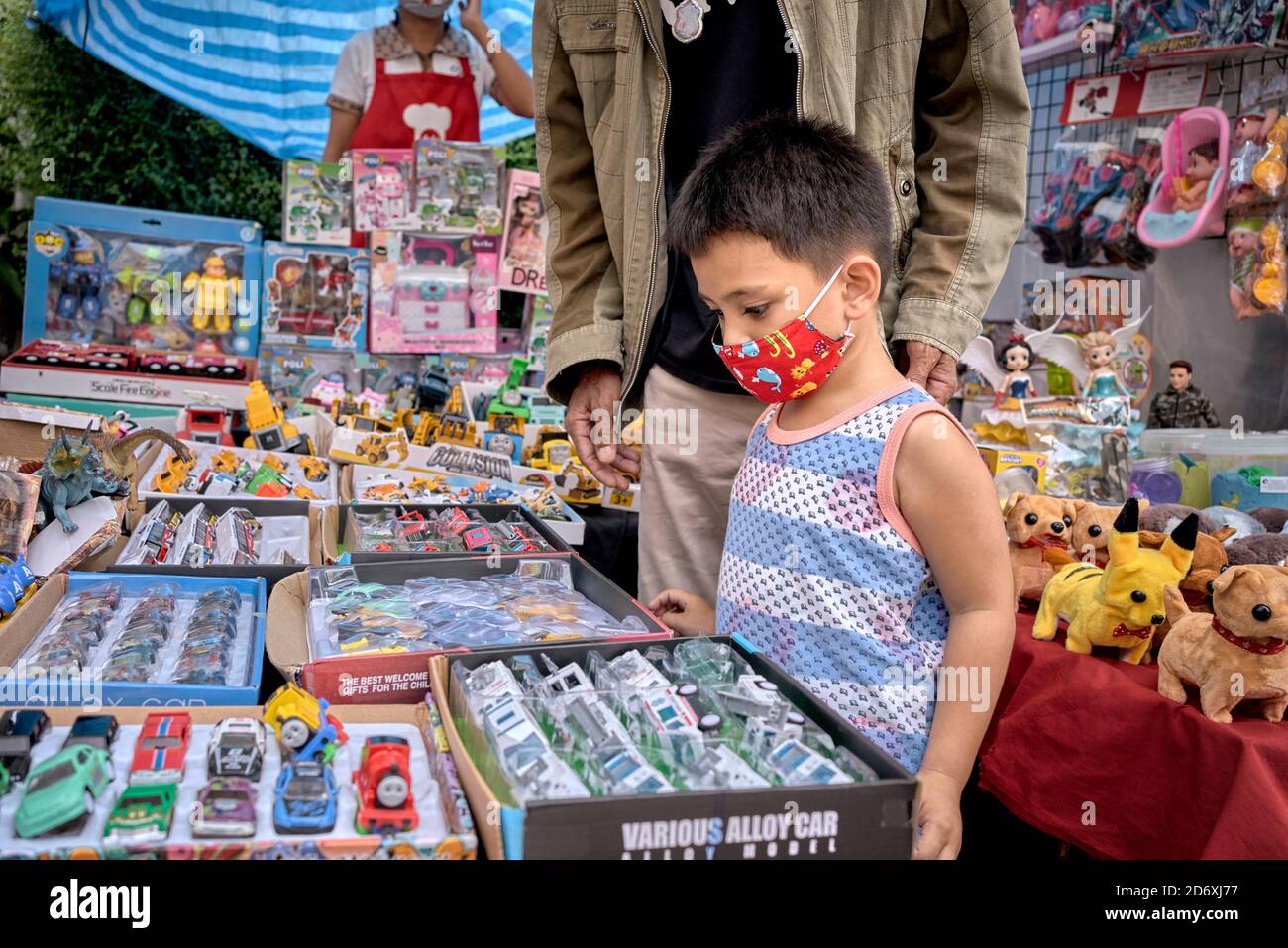 Entscheidungszeit. Zeit zur Auswahl. Kleiner Junge an einem Spielzeugstand, wenn man bedenkt, welches Spielzeug man kaufen soll. Thailand Südostasien Stockfoto