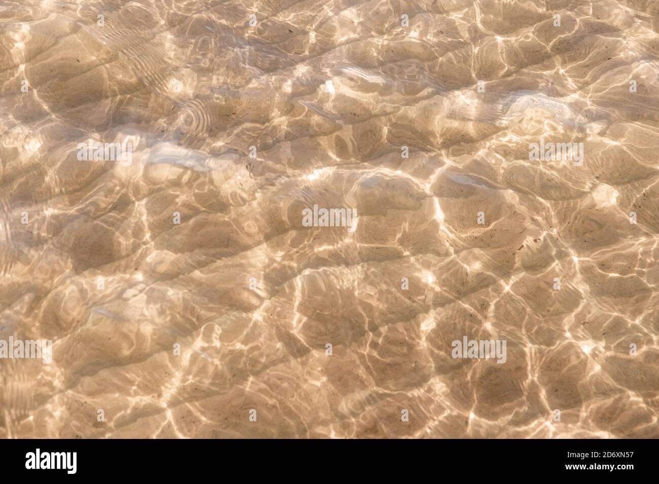 Sandiger Meeresboden unter seichtem Wasser mit Brechungsmuster Stockfoto
