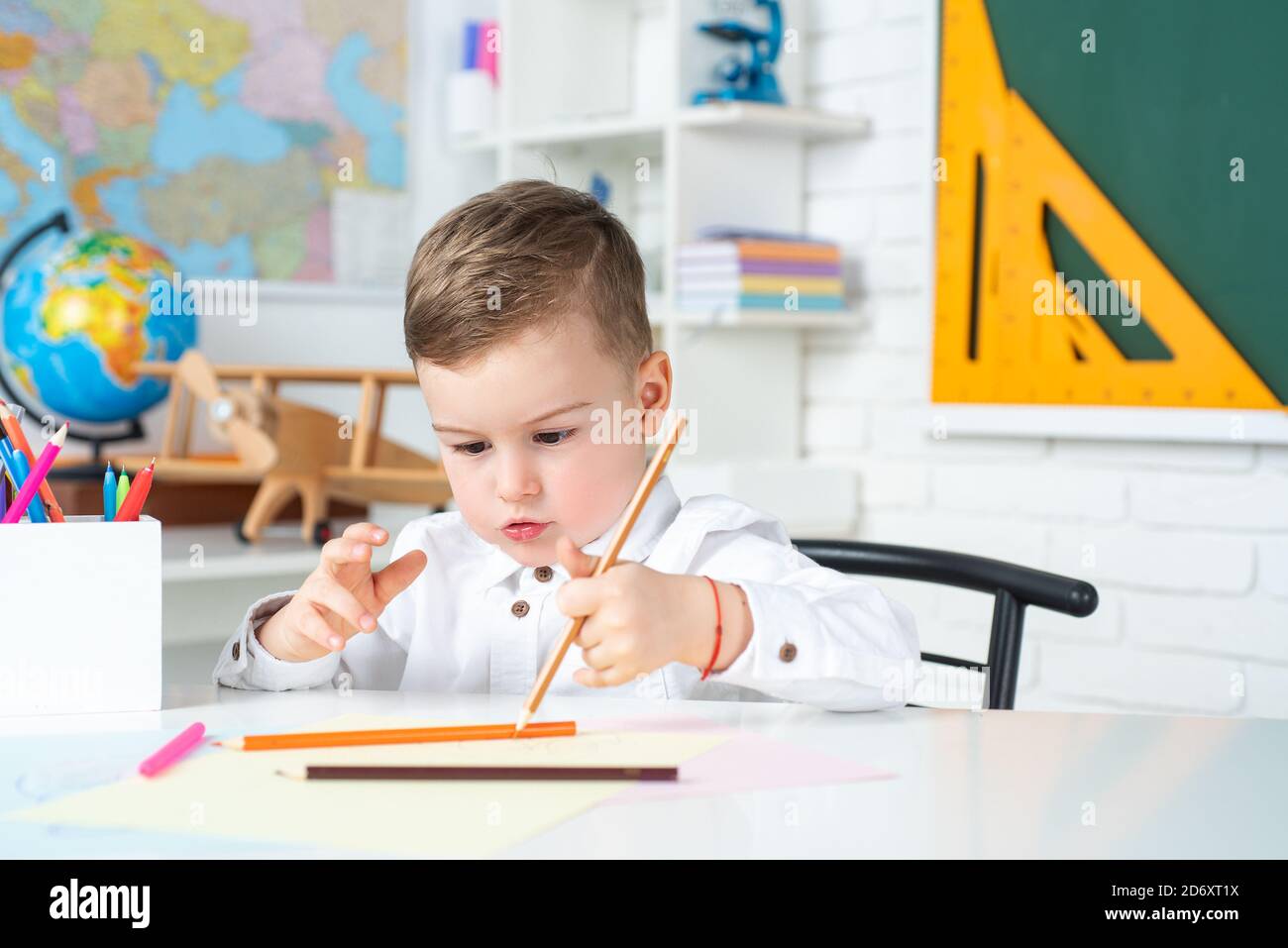 Konzentrierter Schuljunge, der am Schreibtisch sitzt und schreibt. Schuljunge studieren Hausaufgaben während ihrer Lektion zu Hause. Stockfoto
