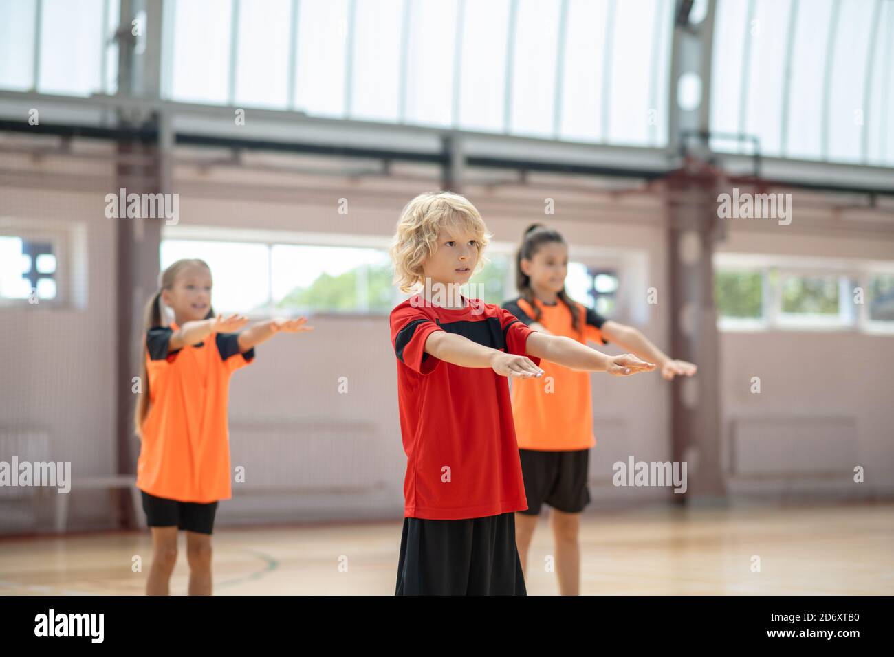 Drei Kinder trainieren im Fitnessstudio und strecken die Arme Stockfoto