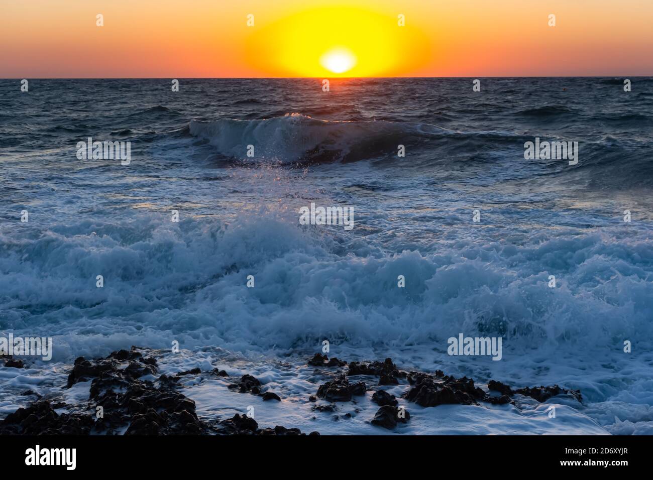 Sonnenuntergang und Sturm auf dem Meer. Große Wellen gegen die untergehende Sonne. Sommersturm auf dem Schwarzen Meer. Schönes Meeresspray mit Schaumbrüchen an der felsigen Küste. Be Stockfoto