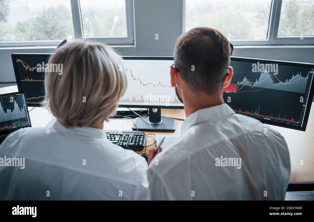 Zwei Börsenmakler in formeller Kleidung arbeiten im Büro mit Finanzmarkt Stockfoto