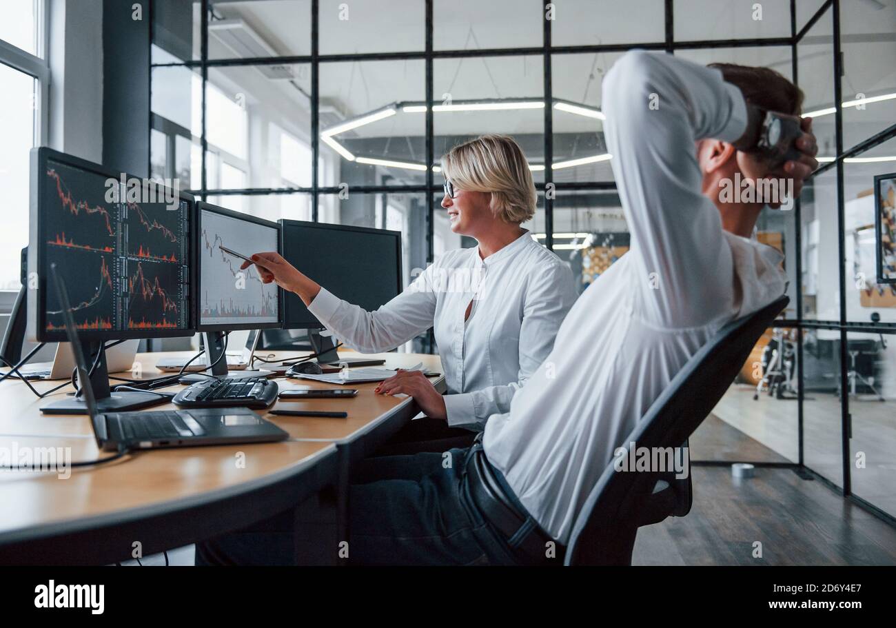 Zwei Börsenmakler in formeller Kleidung arbeiten im Büro mit Finanzmarkt Stockfoto