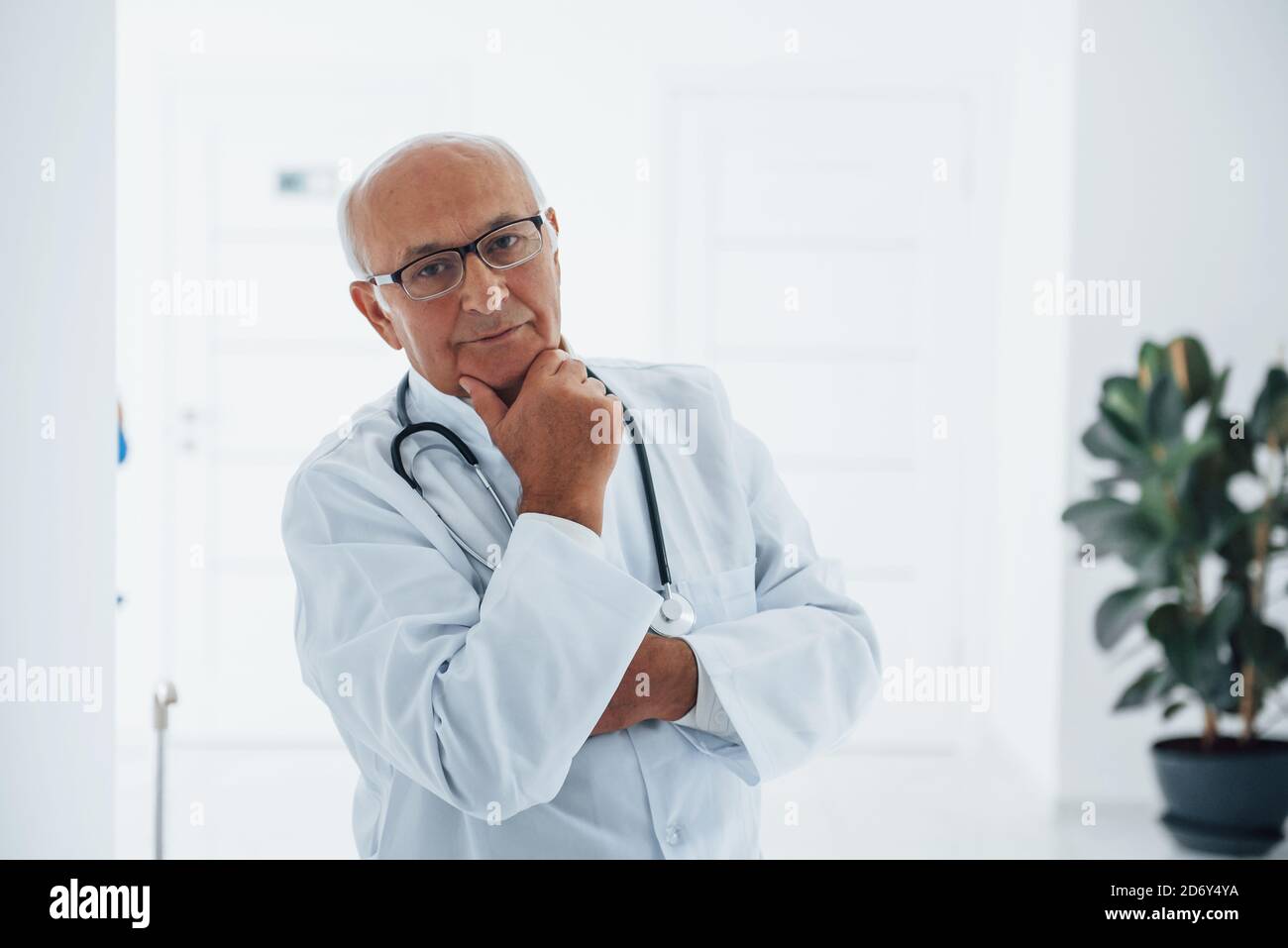 Porträt eines älteren Arztes in weißer Uniform, die in steht Die Klinik Stockfoto