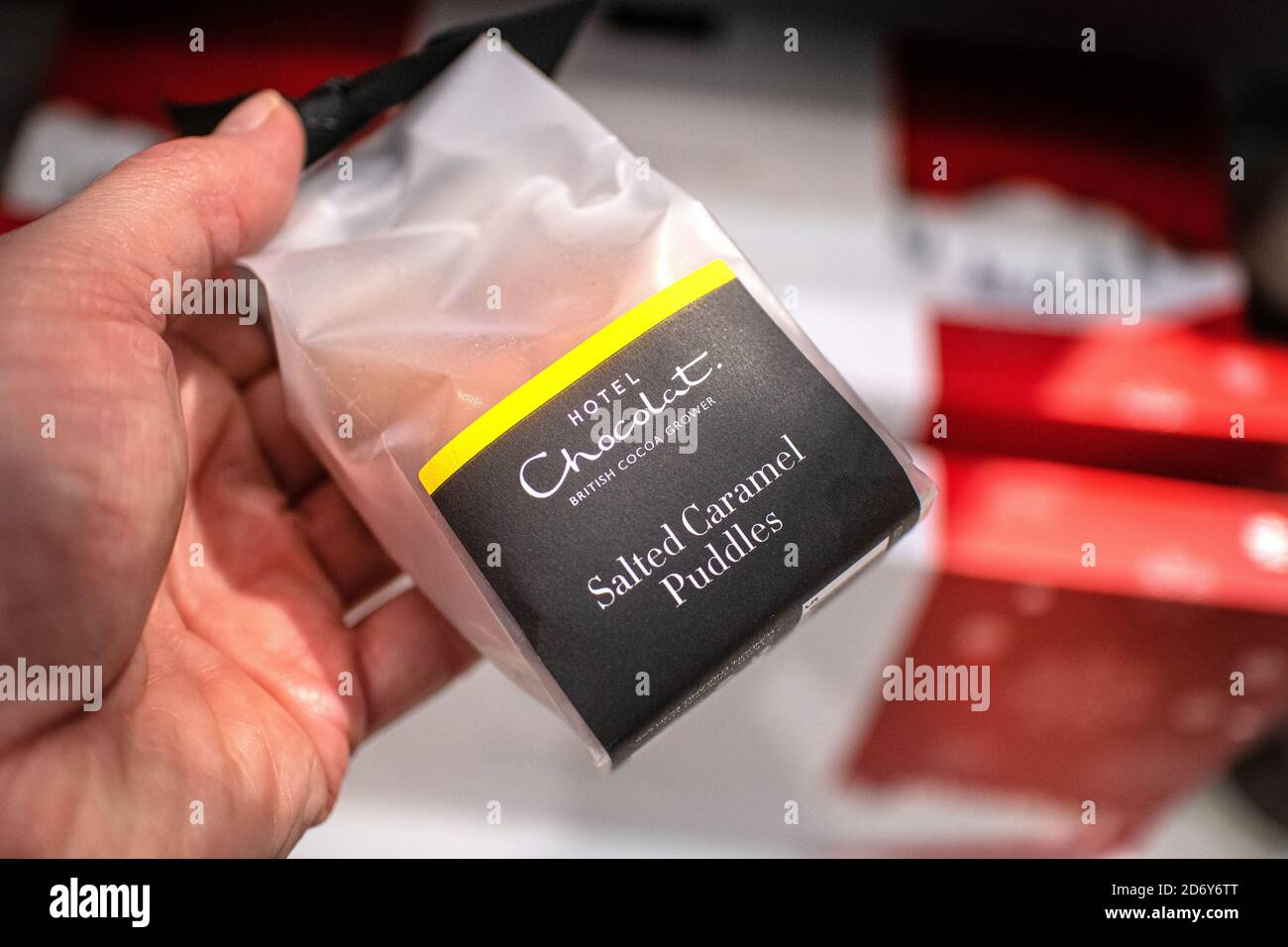 Hand hält eine Packung Hotel Chocolat gesalzene Karamellpfützen. Das Hotel Chocolat ist ein britischer Chocolatier- und Kakaoanbauer der Spitzenklasse. Stockfoto